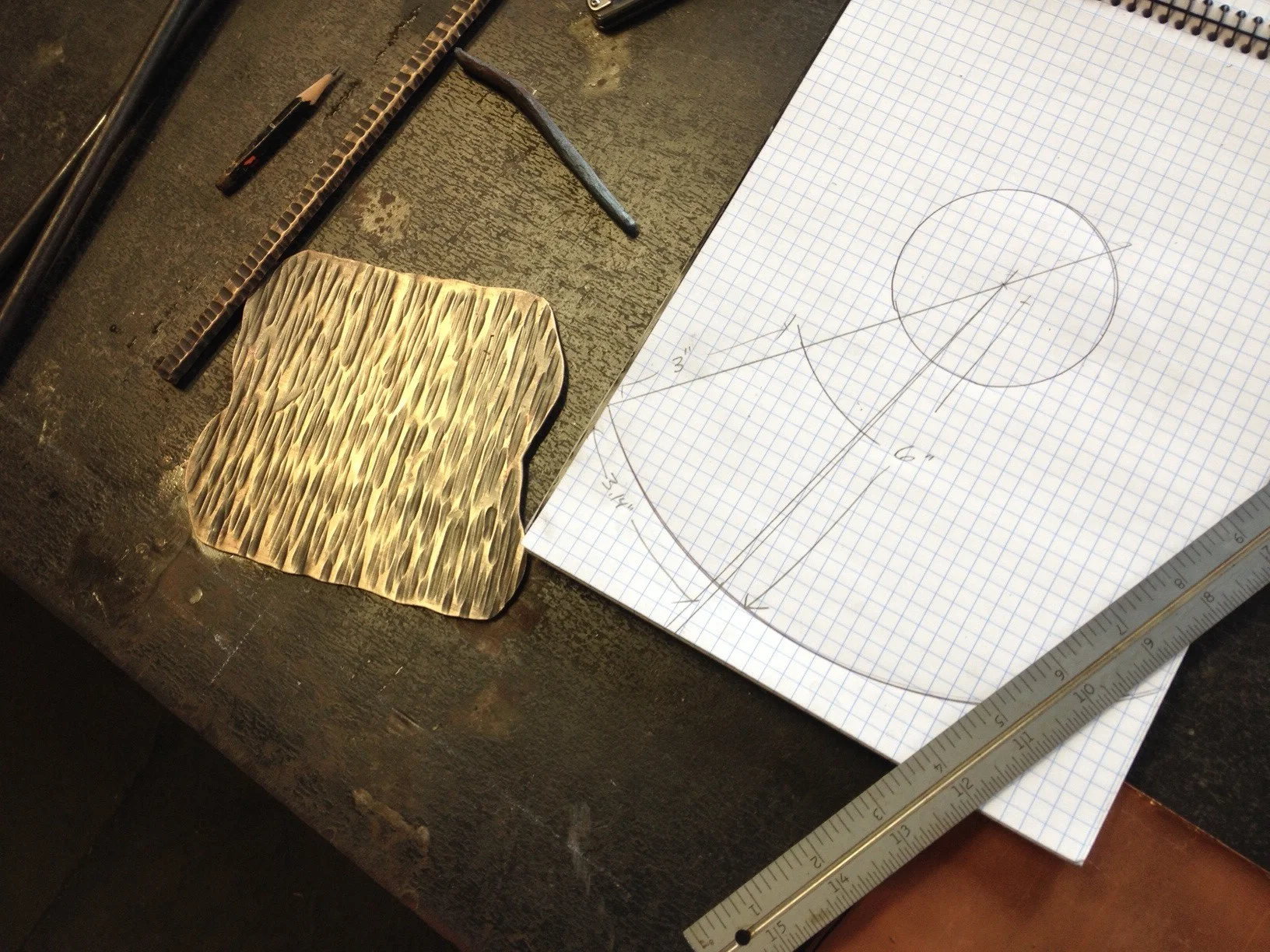 Kyle created sheet metal for this project by forging down a block of bronze to 1/16" thick. He gave the bronze some hammer texture for added depth. Here he's l aying out the frustum, or a cone without it's tip, that he'll use for the base of the tree topper.