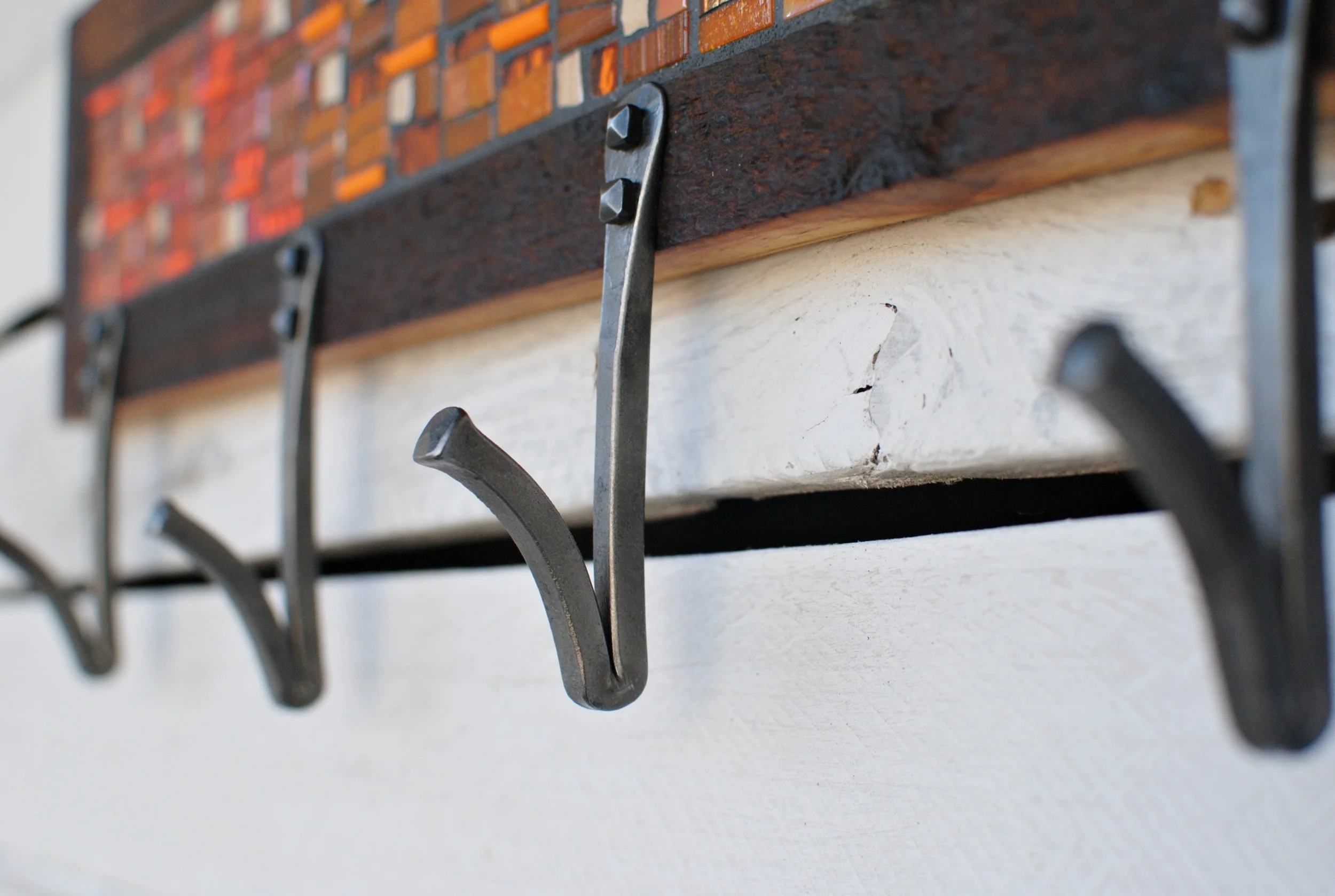 Detail of hand-forged steel V-hook on a custom mosaic coat rack