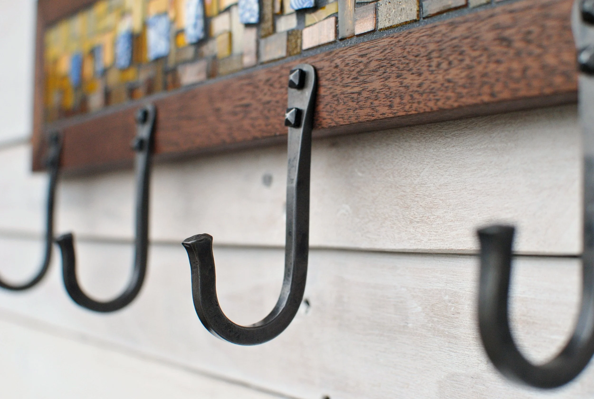 Detail photo of hand-forged hooks on mosaic coat rack