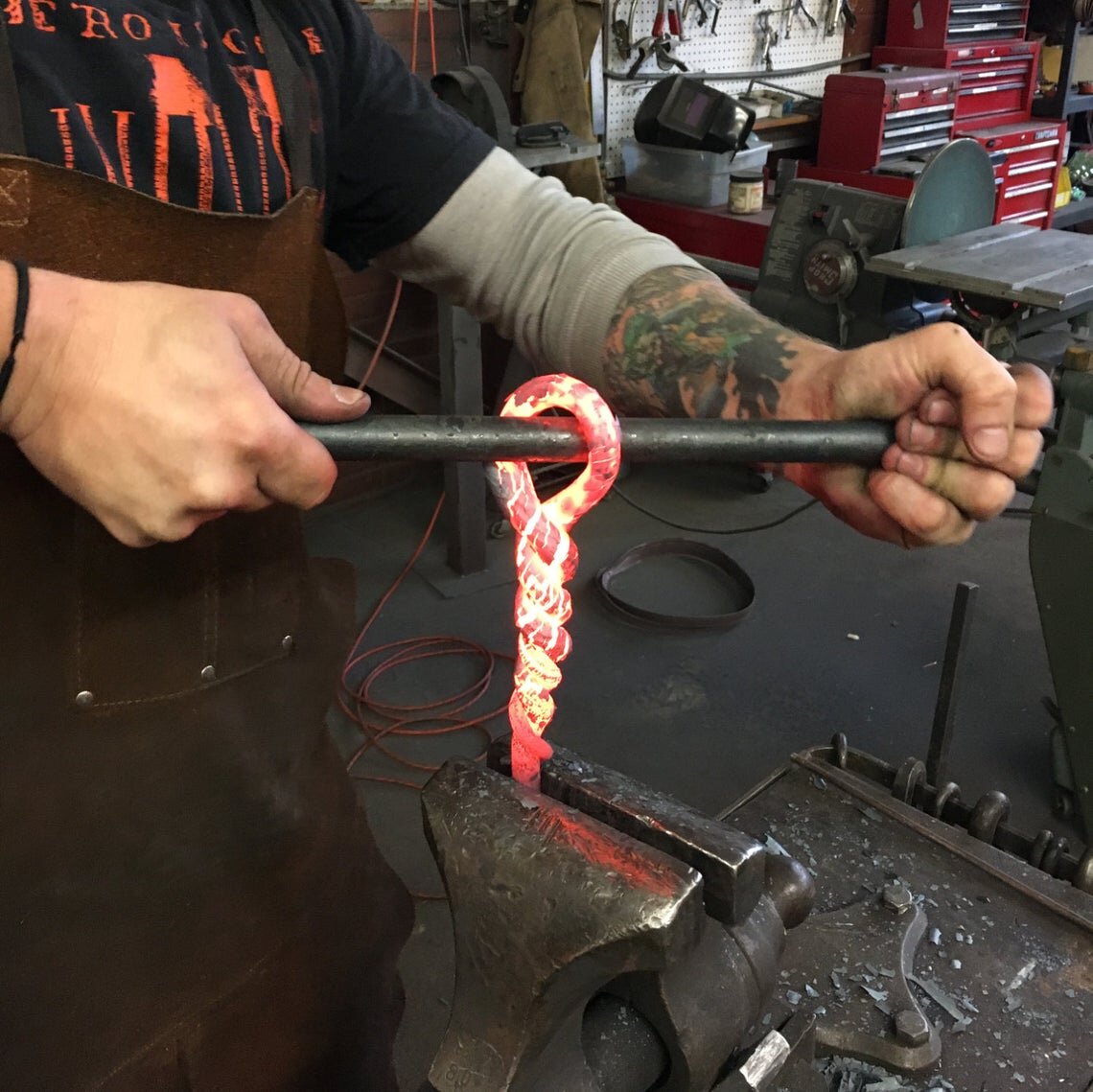 Hot forging twisted handle bonfire poker using a post vise