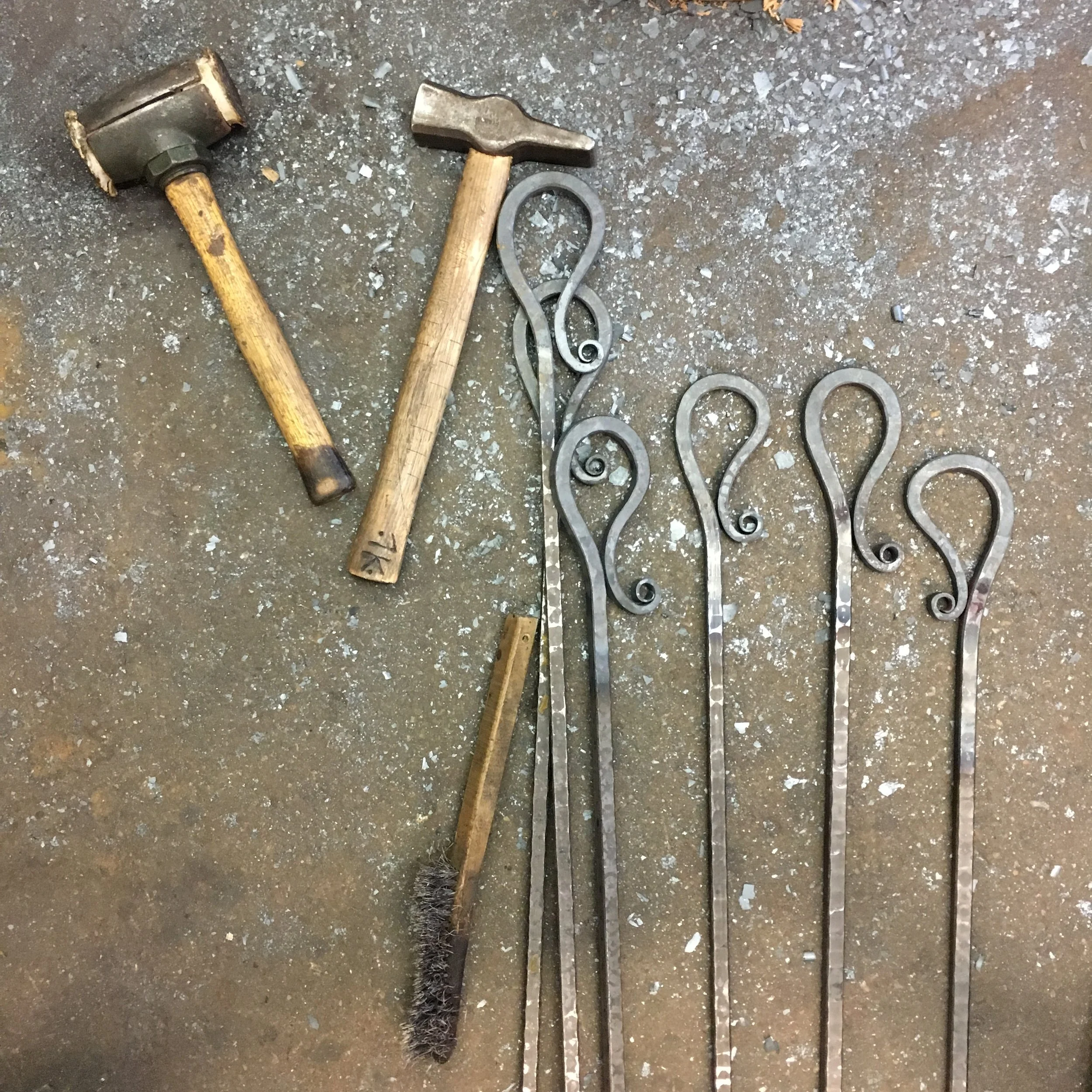 Group of shepherd's crook handle  outdoor fire pokers in process on blacksmith shop floor