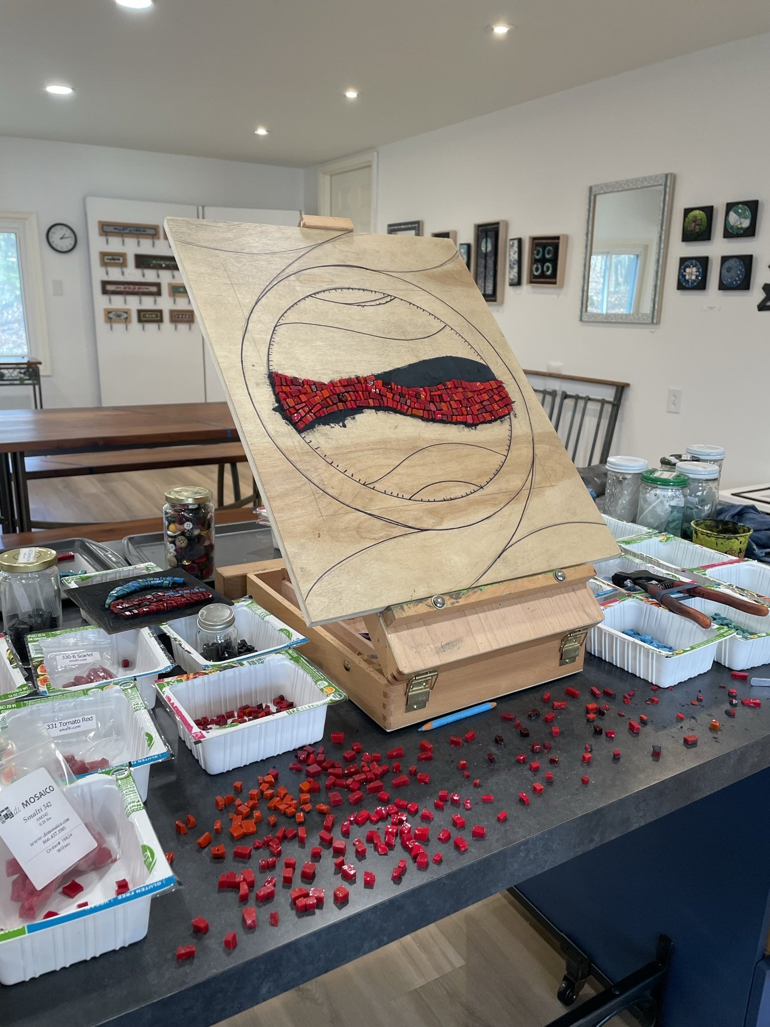 Red and blue mosaic art in progress on easel