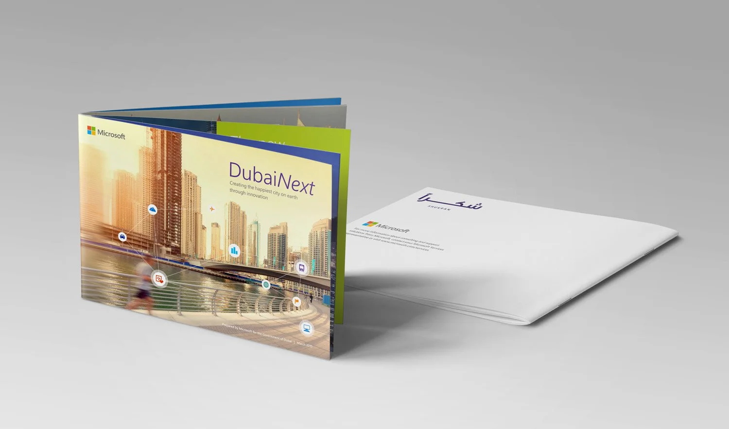 A mostly closed booklet stands upright on its pages in the forefront showcasing the cover. Another booklet is behind it, lying flat on the surface showing the back cover.