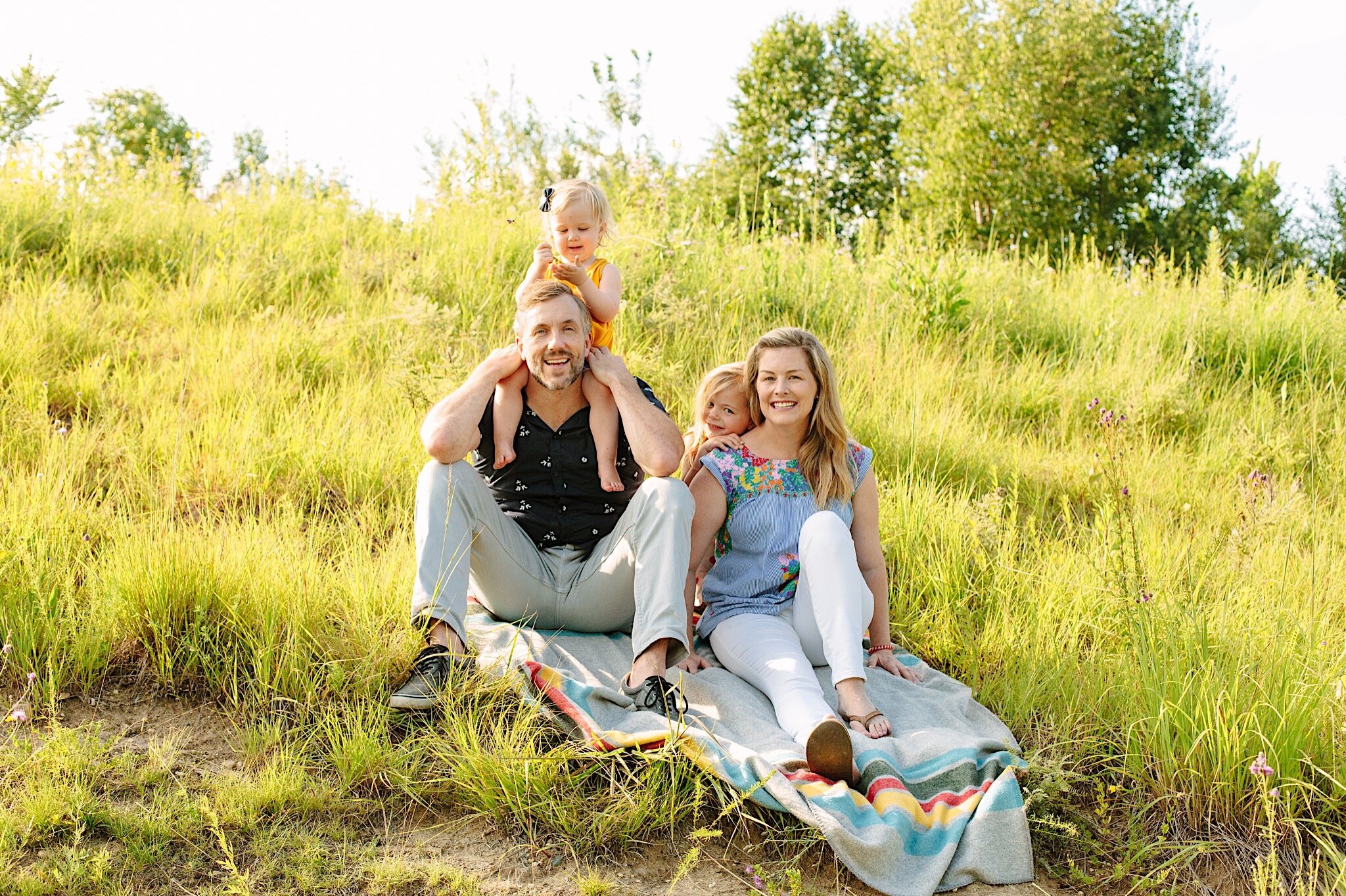 A family of four sitting together in the tall grass at Bush Lake in Bloomington, Minnesota