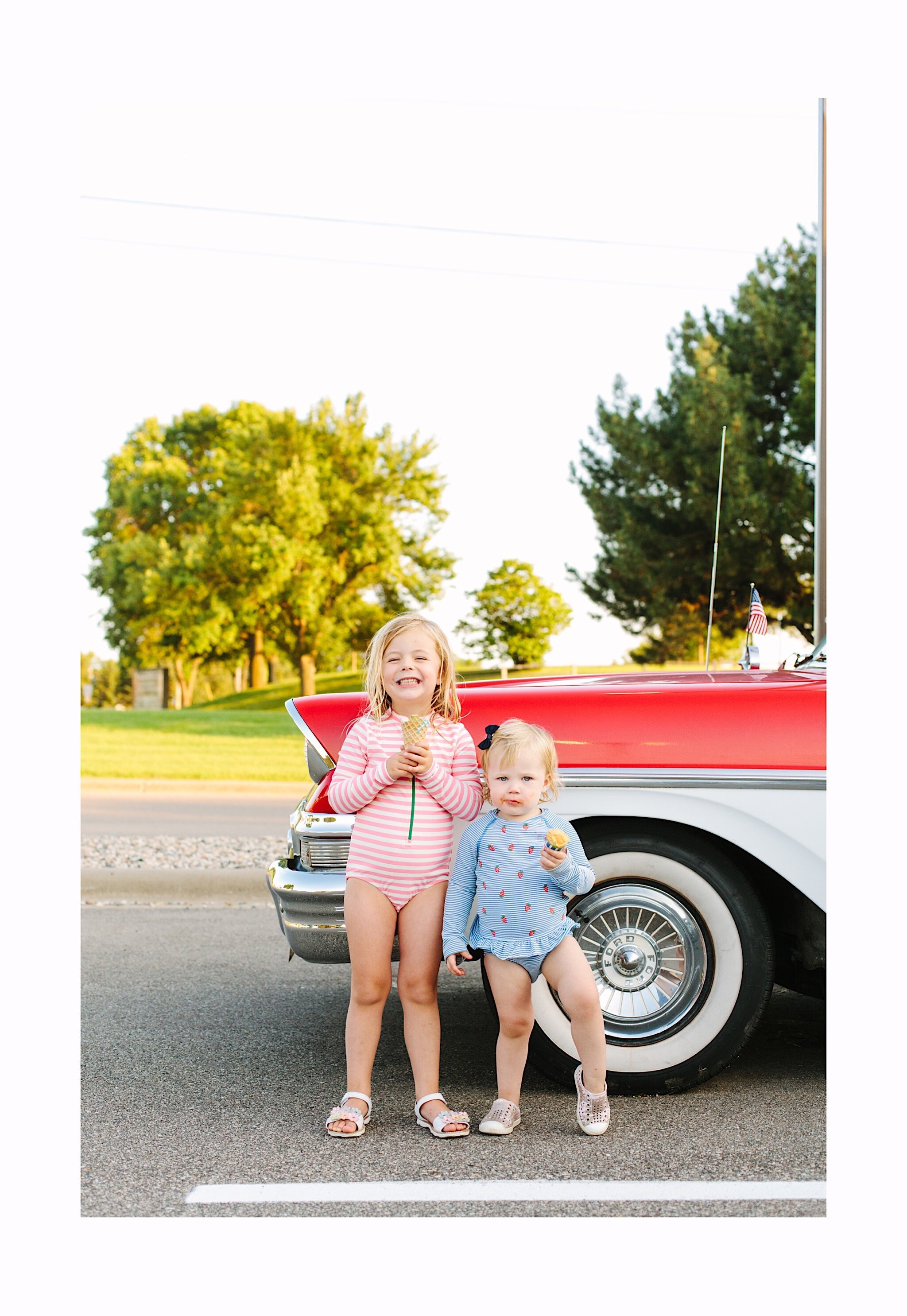 Photo of two sisters eating ice cream by a red and white vintage car