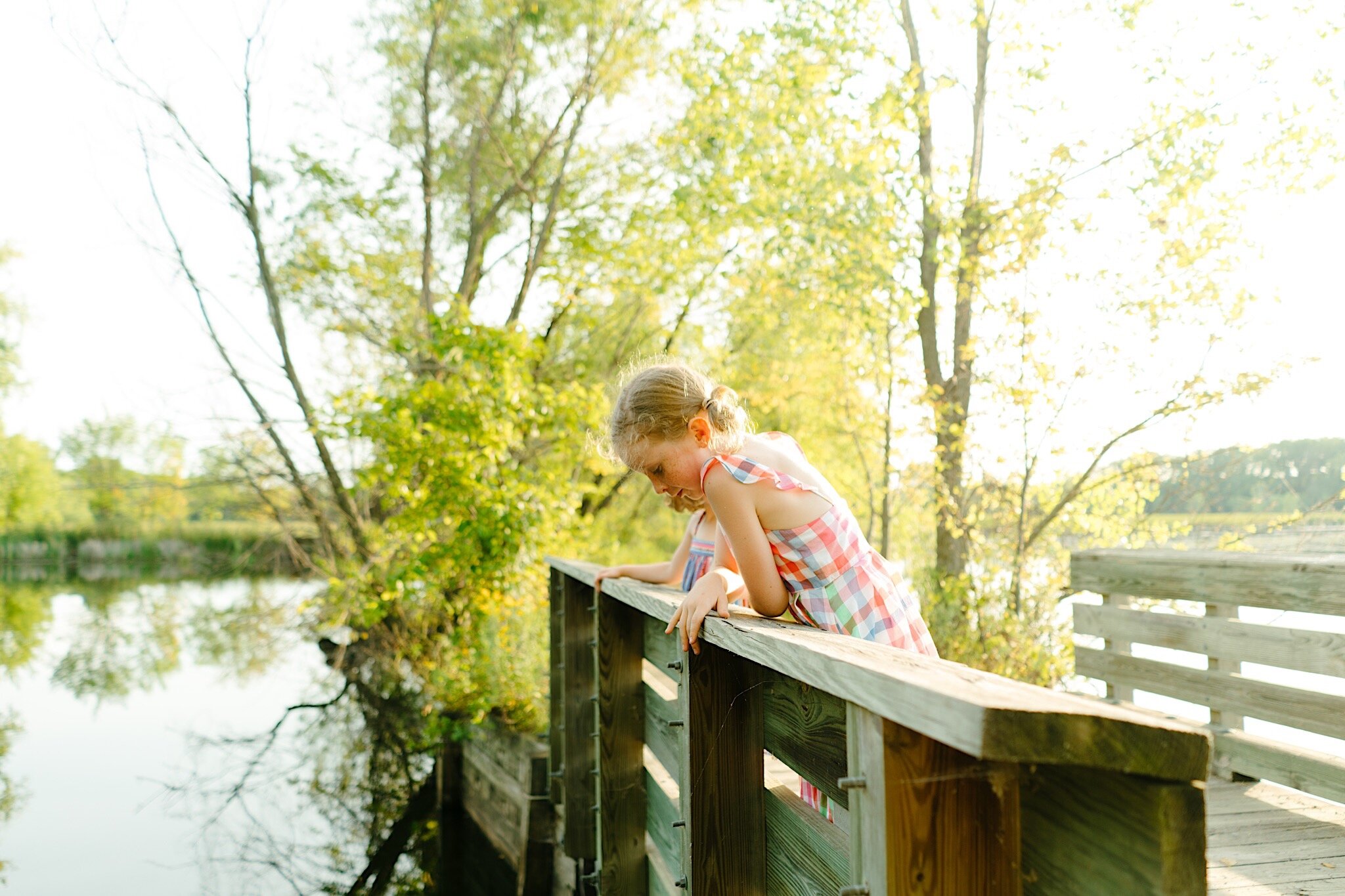 A young girl looking over the side of a bridge during a family photo session in Minneapolis, Minnesota