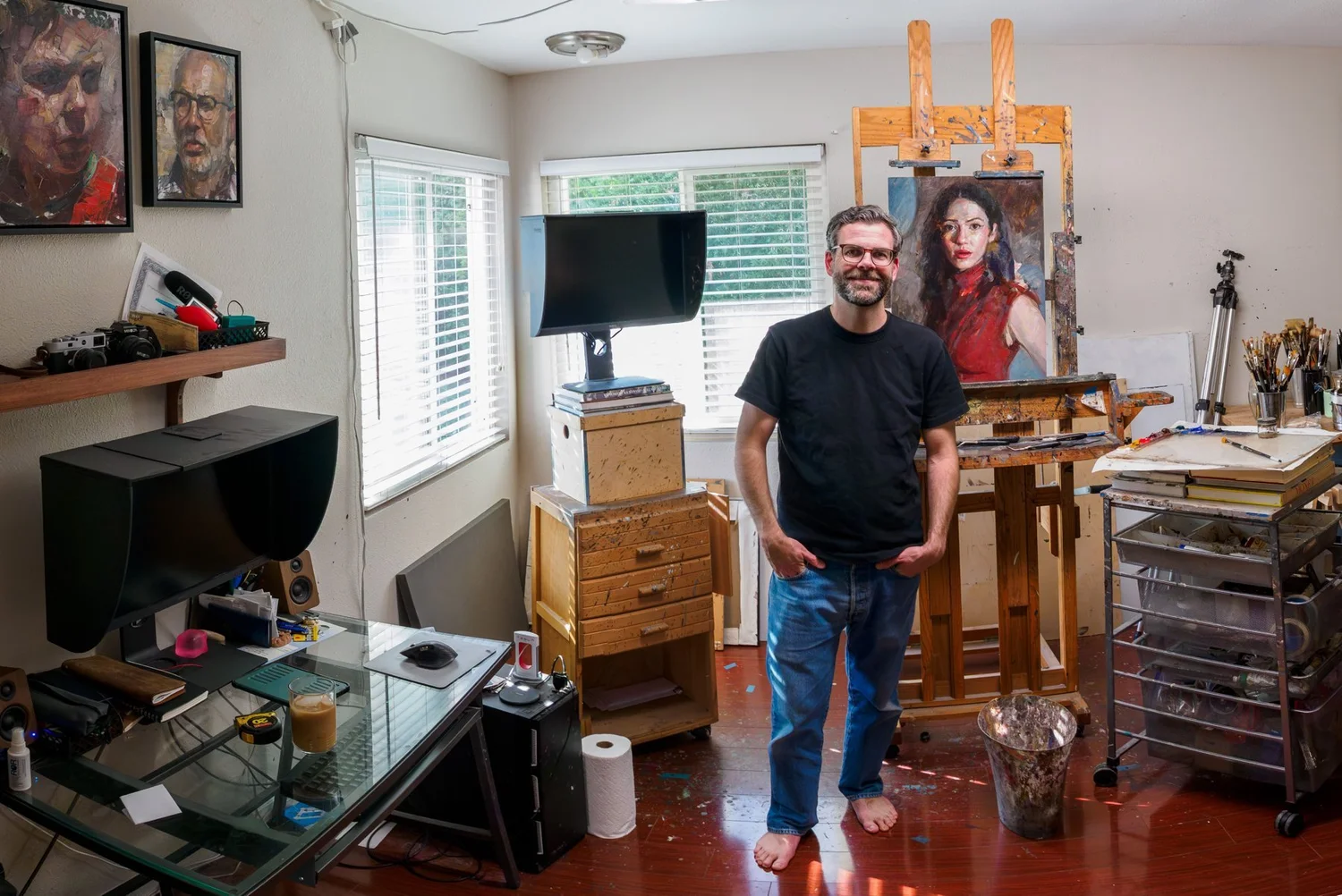Matt Talbert in his painting studio, beside an easel with a portrait in progress