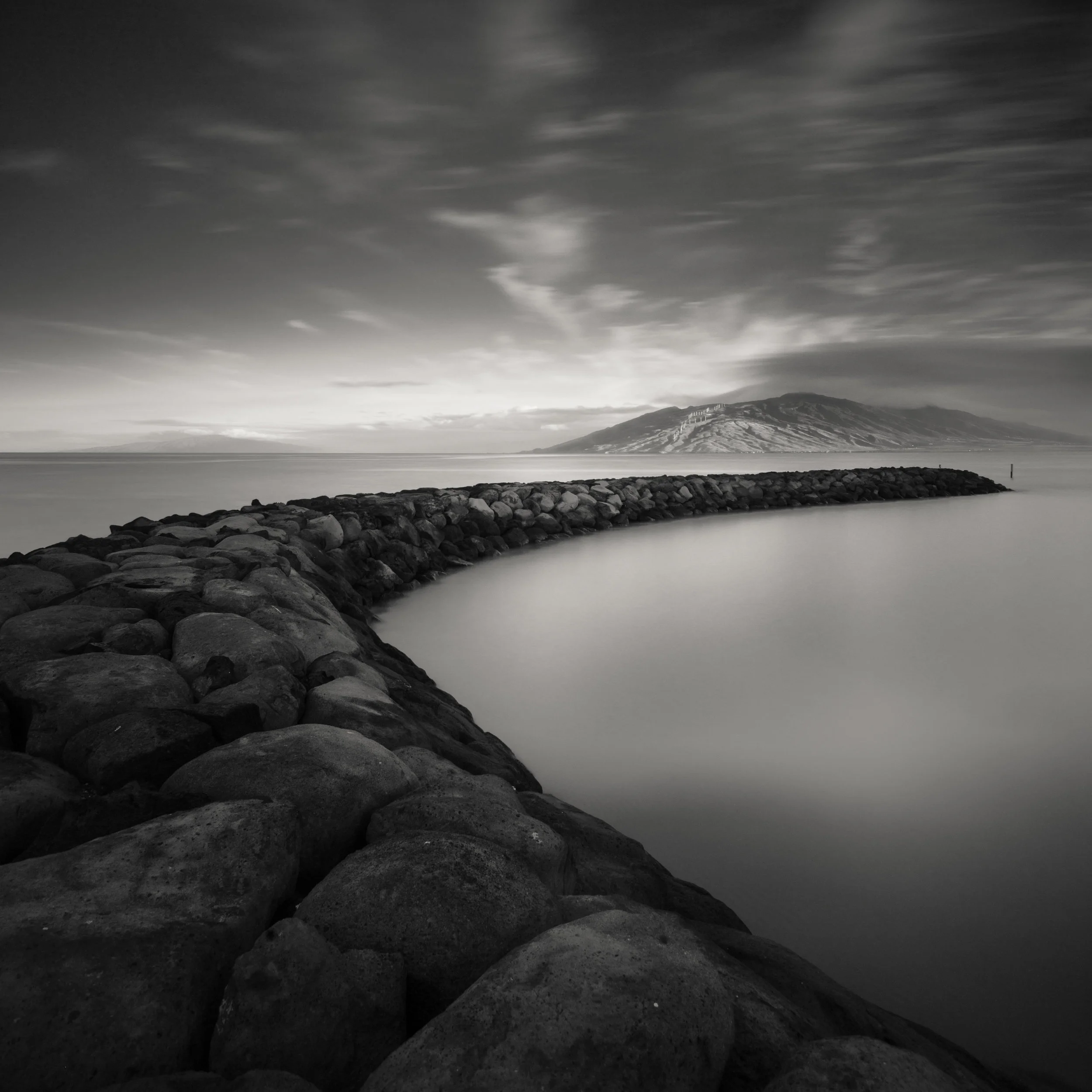 Maui Kihei black white curved jetty distant mountains