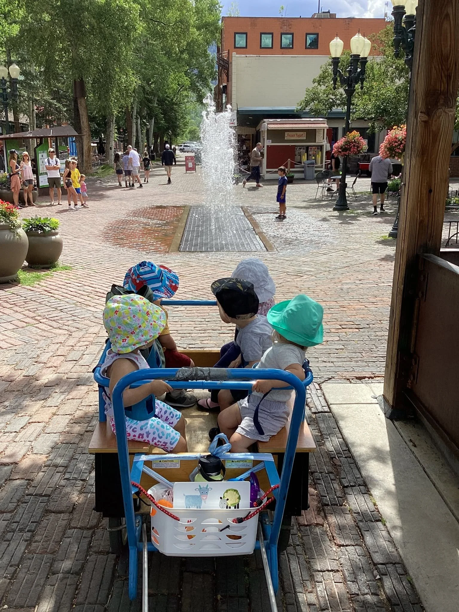 Children riding in a buggy downtown Aspen near the fountain.