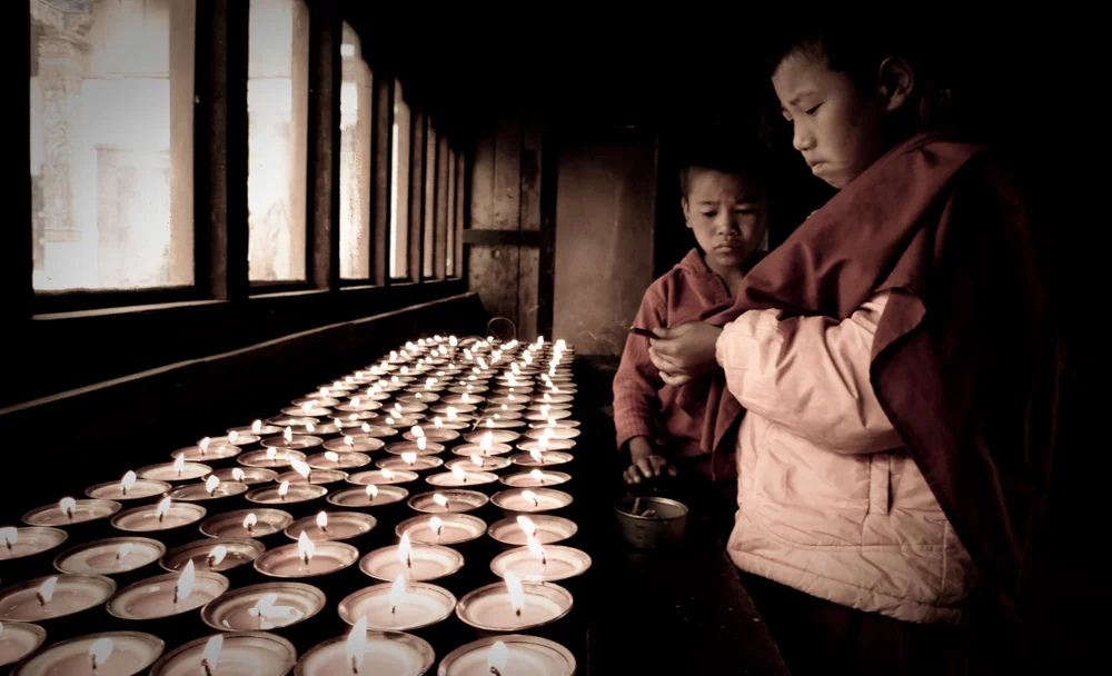 young monks lighting candles