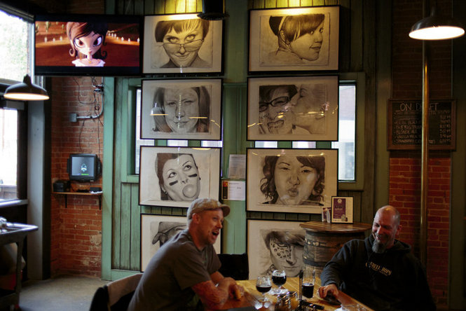 Two men talk over drinks at The Mitten Brewing Company where the "Faces of Michigan Roller Derby" look on from the background. The 2014 ArtPrize two-dimensional drawings were created by Megan Foldenauer, Grand Rapids, Mich., Thursday October 2, 2014. (Joel Bissell | MLive.com)