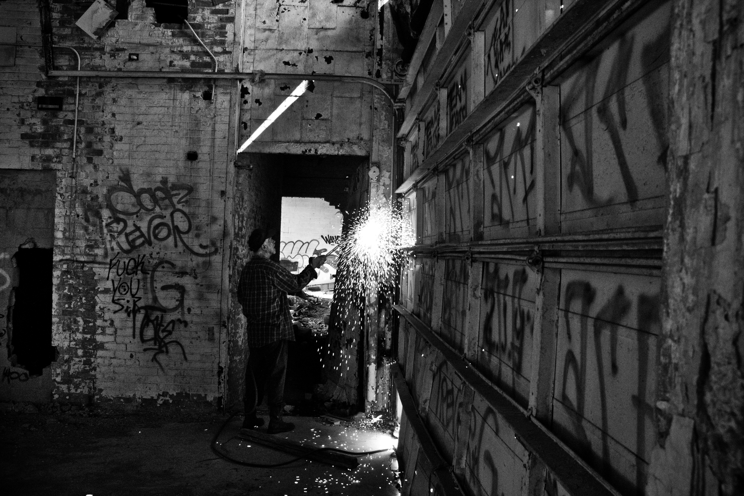 A local scrapper cuts the metal frame of a bay door at the Packard Plant, Detroit. 