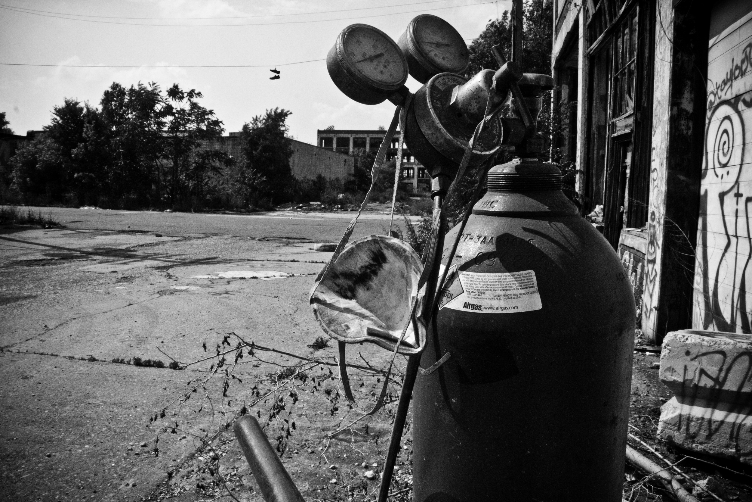 A mobile torch and tank sit outside an entrance to the Packard Plant while a scrapper searches inside for valuable metal. 