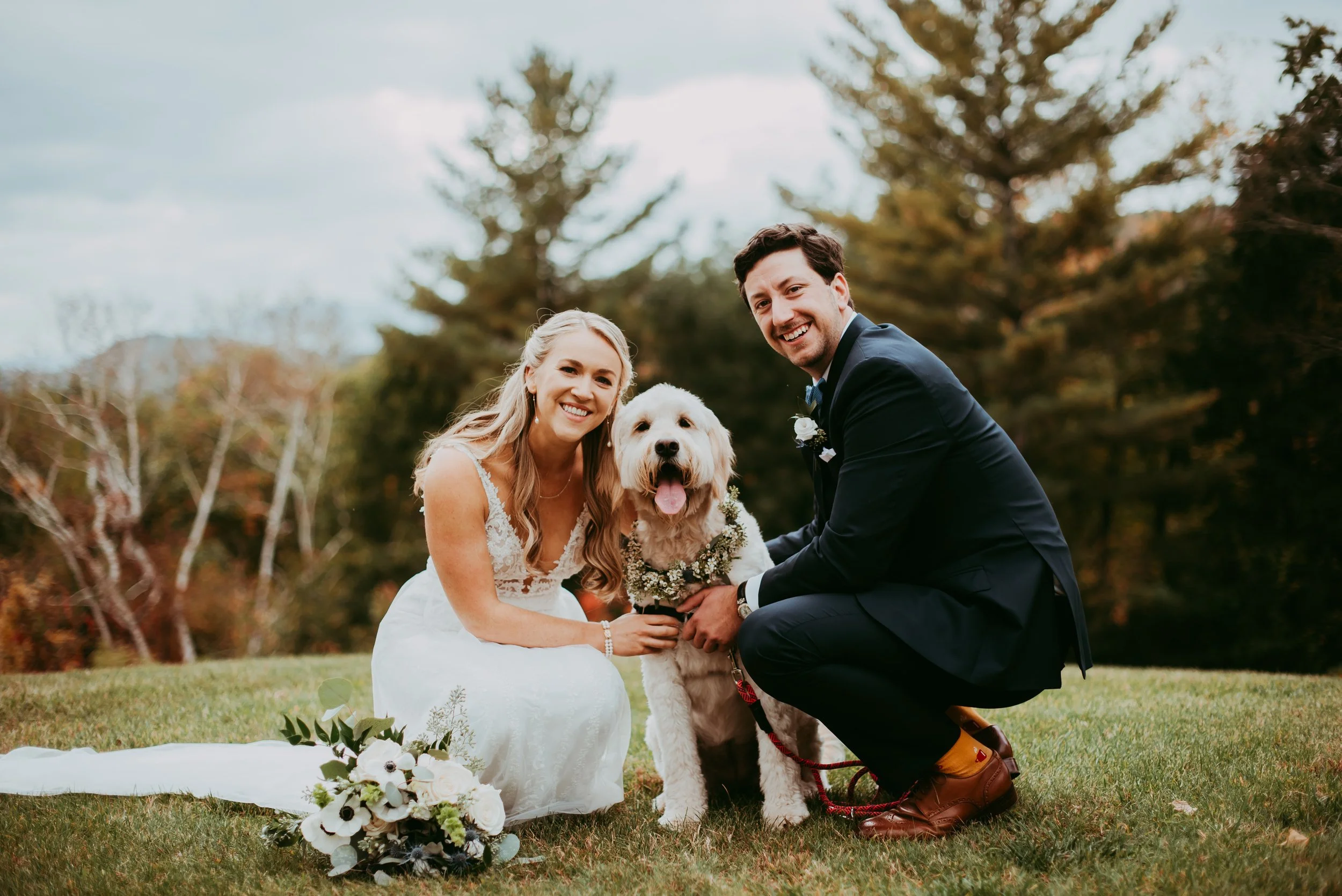 a man and woman sitting on grass with a dog