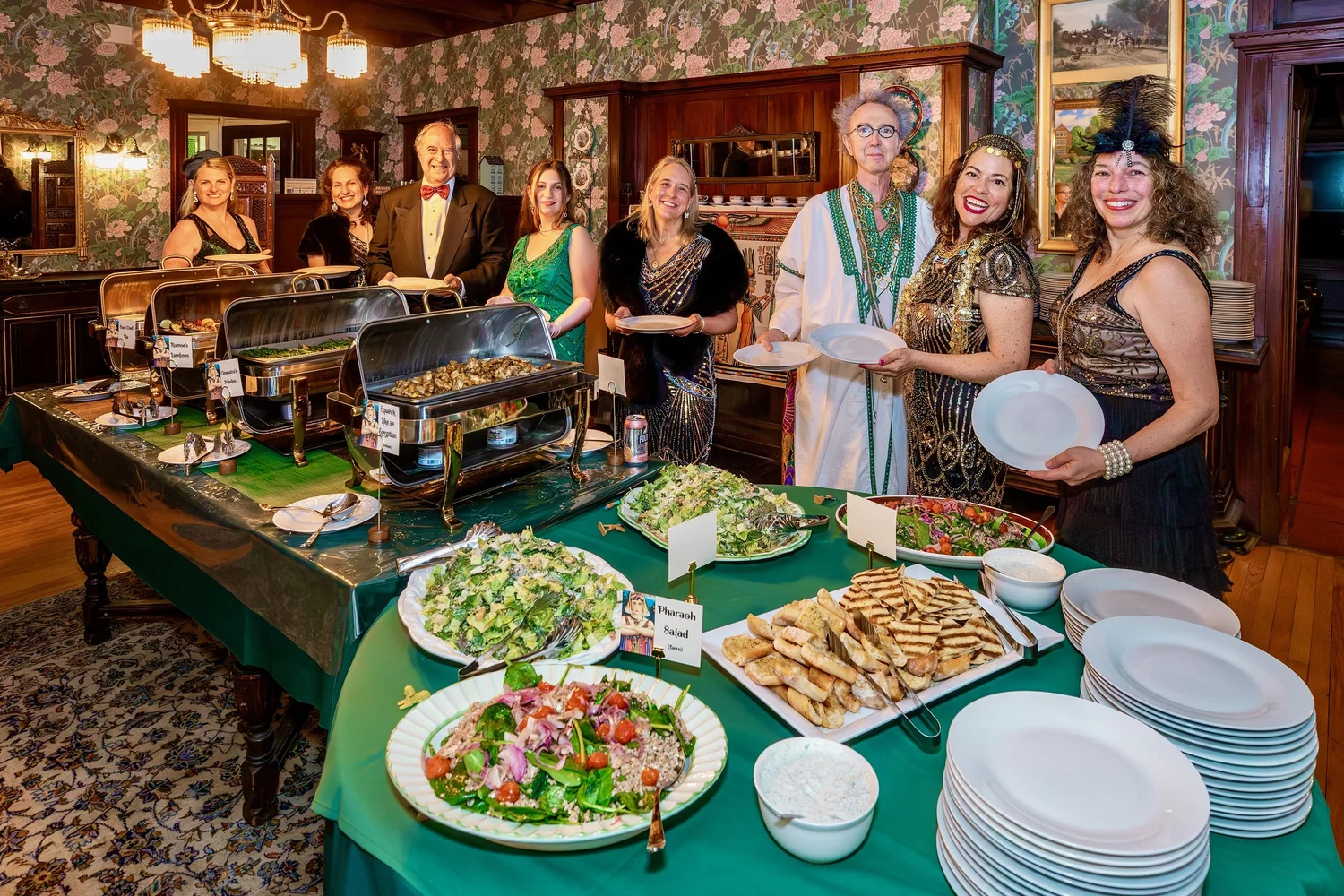a group of people standing around a table with food on it