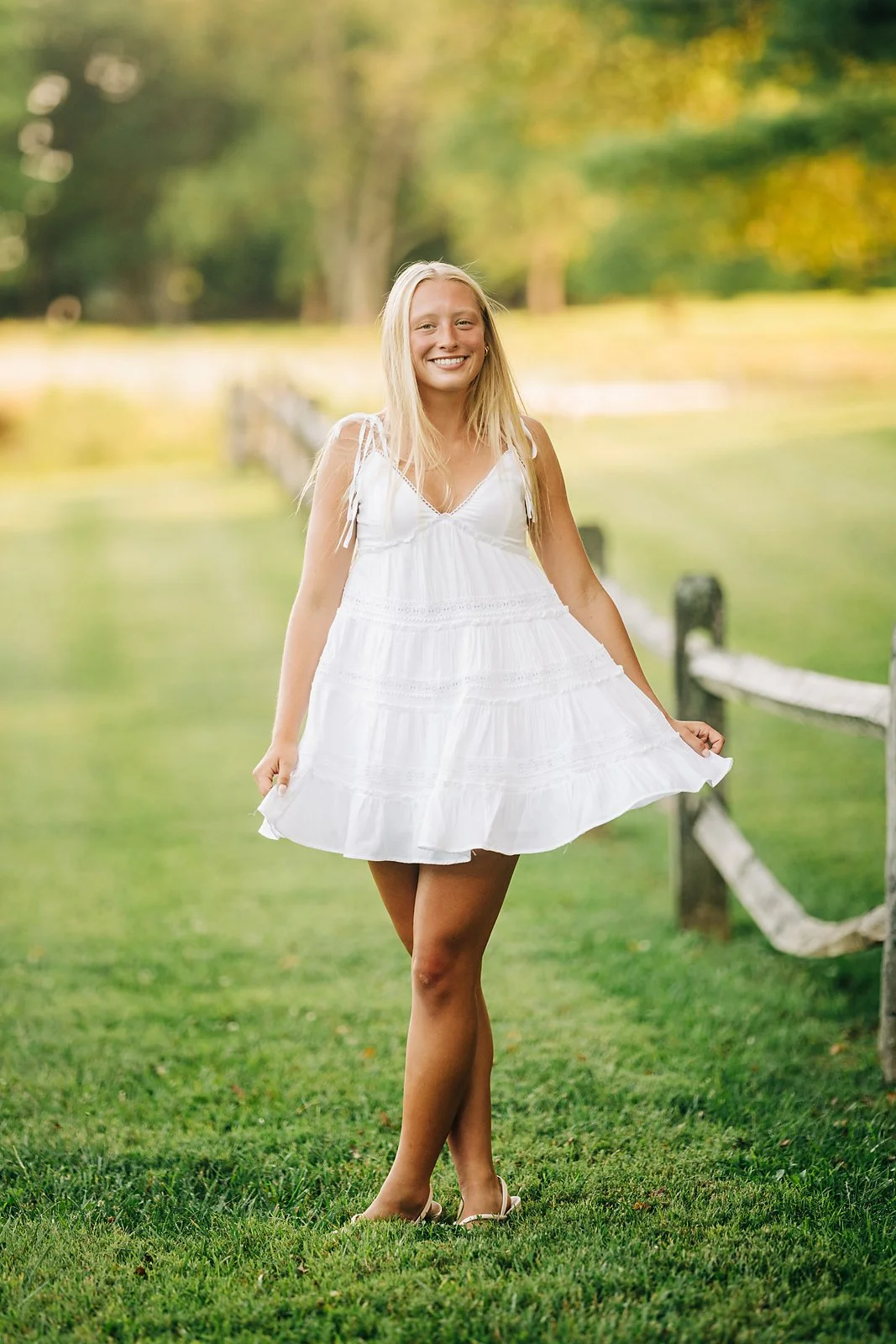 Northwestern Lehigh senior Kherinton in a white dress beside a rustic wooden fence during her summer senior session.