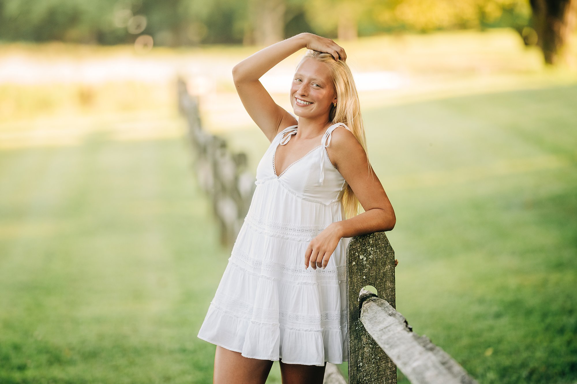 Northwestern Lehigh senior Kherinton in a white dress beside a rustic wooden fence during her summer senior session.