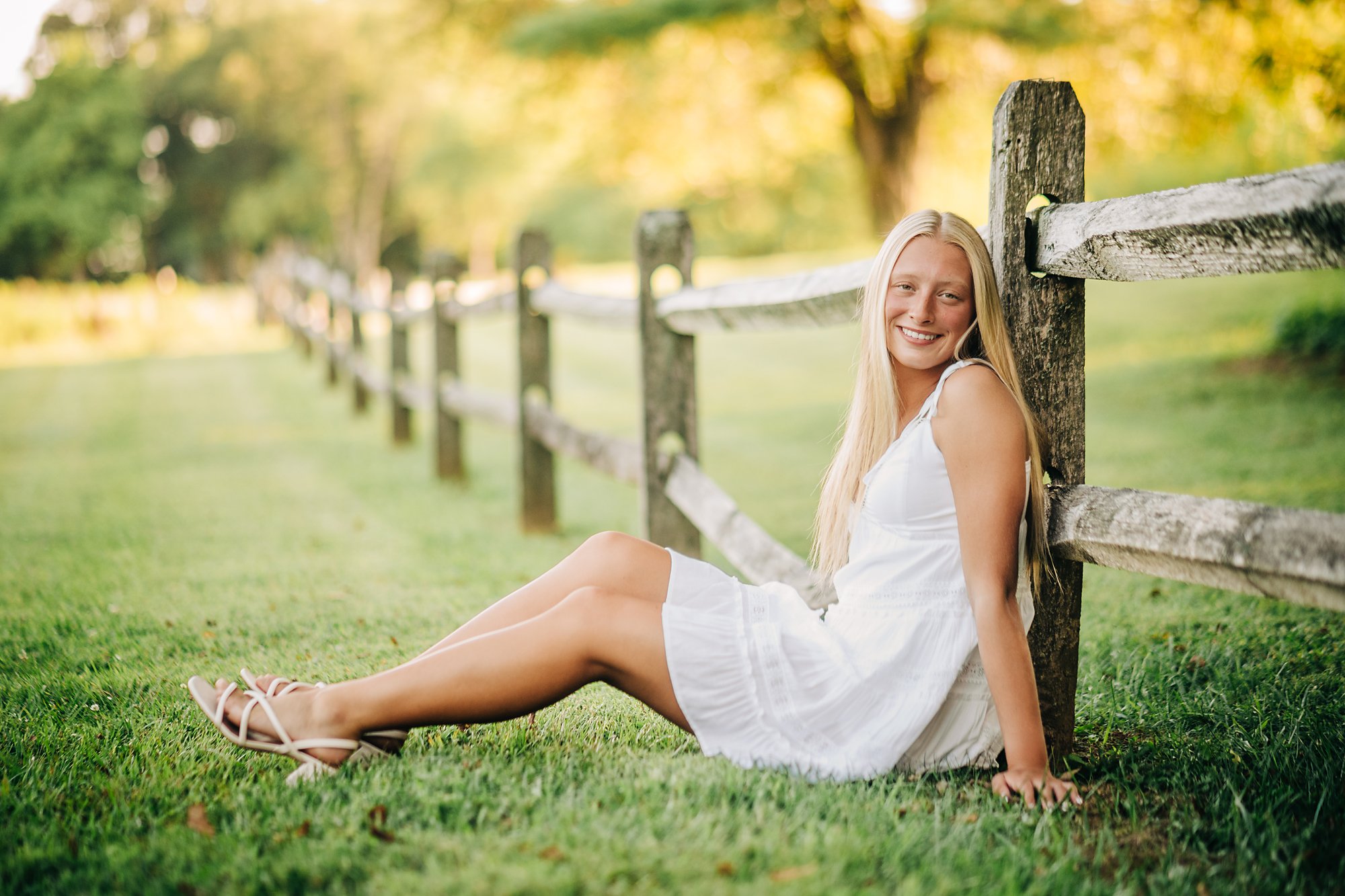 Northwestern Lehigh senior Kherinton in a white dress beside a rustic wooden fence during her summer senior session.