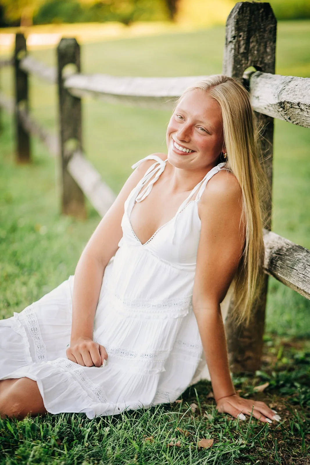 Northwestern Lehigh senior Kherinton in a white dress beside a rustic wooden fence during her summer senior session.