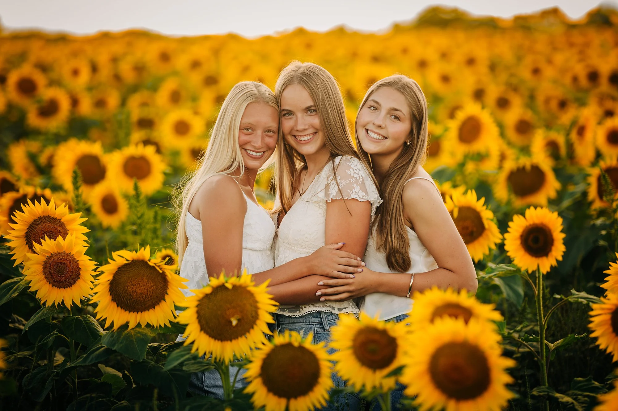 Three friends posing together among sunflowers during a Lehigh Valley senior photography session.
