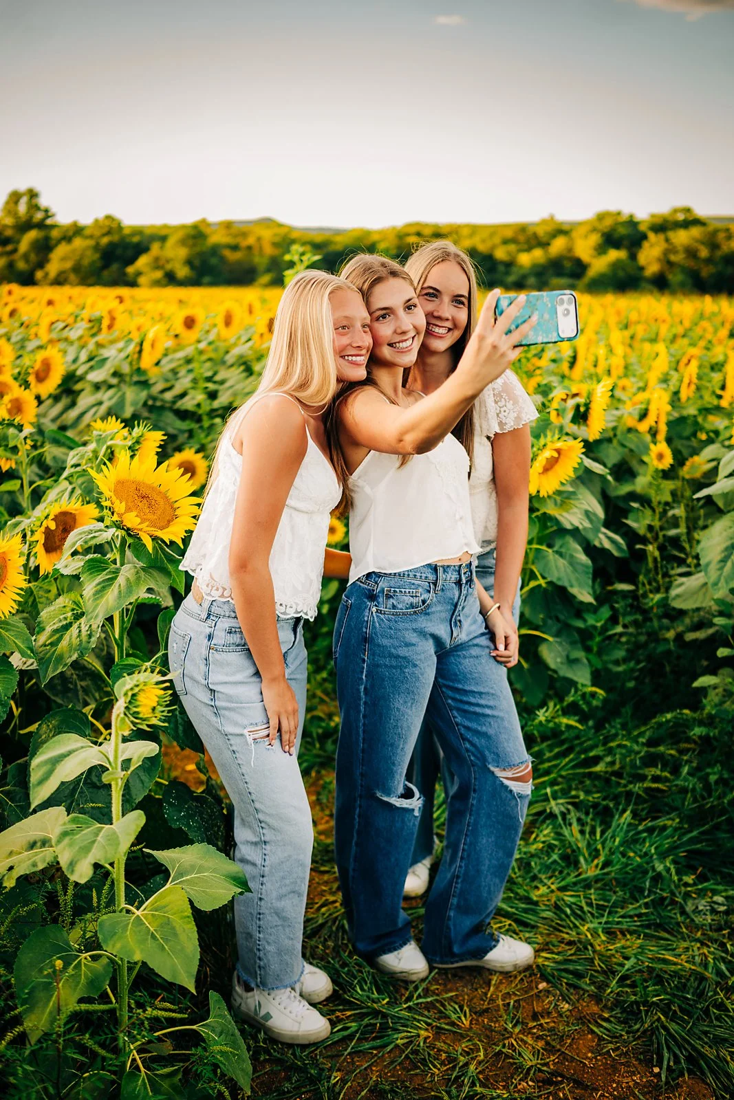 Three friends taking a selfie during their Lehigh Valley sunflower senior photo session.
