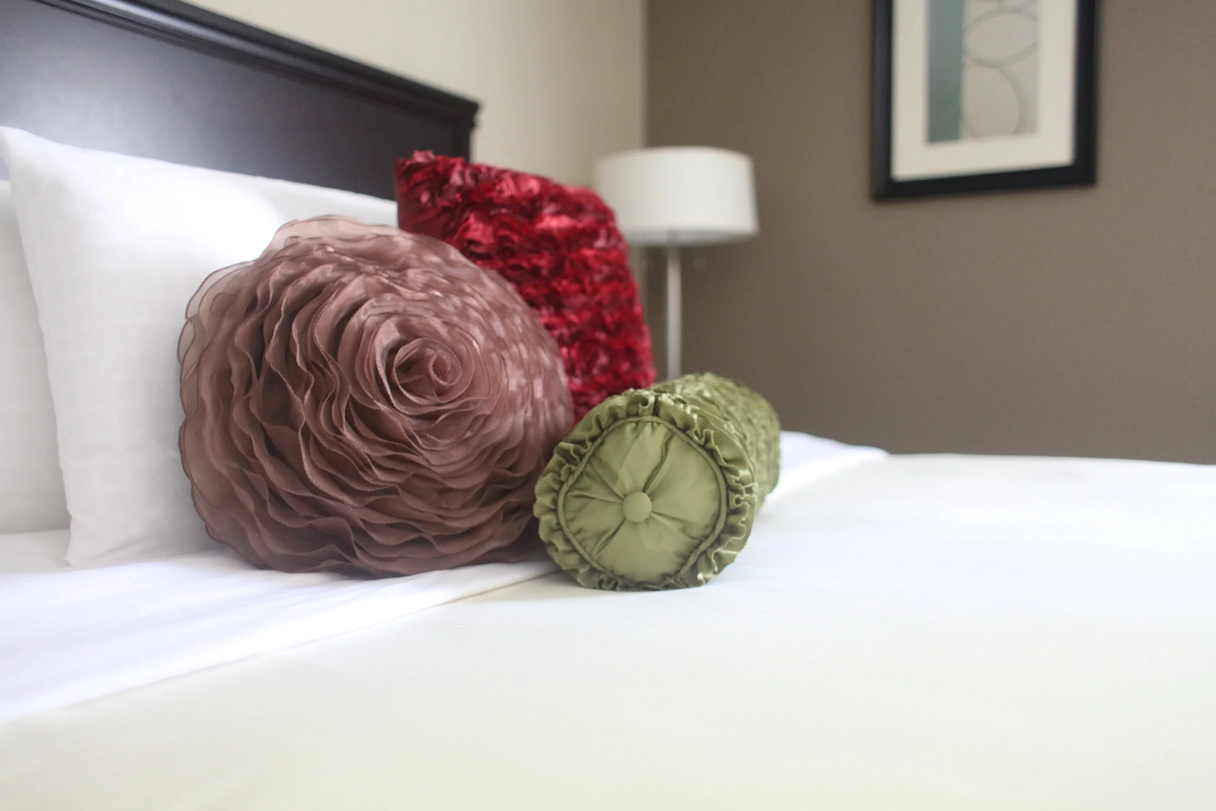 Colorful pillows on a king sized bed in Eastland Suites Bloomington.jpg