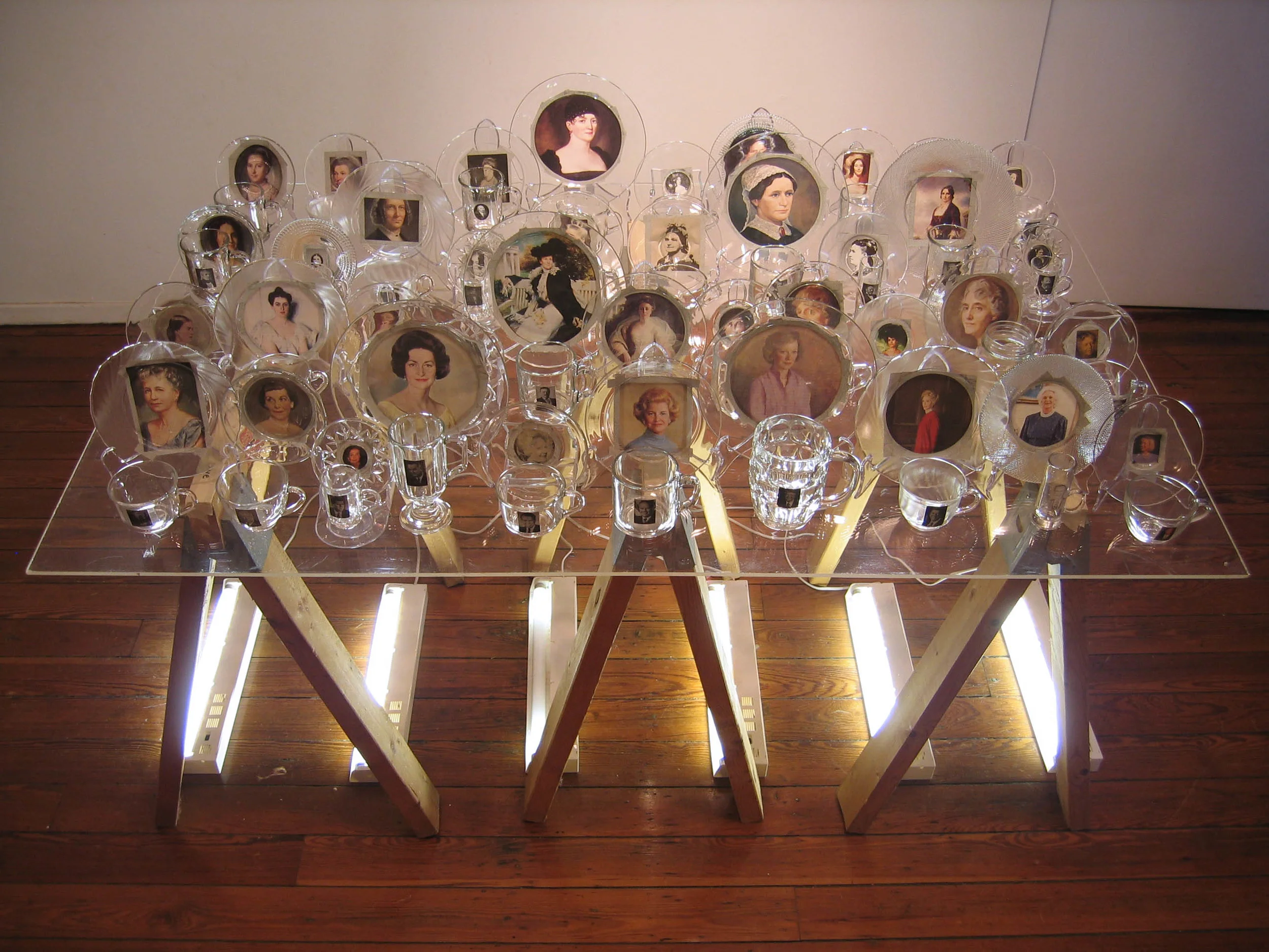First Love, 2007, Glass, paper, tape, plexiglass, wood and fluorescent lights 41 cups with president, 41 saucers with first lady, 4 x 3 x 3'