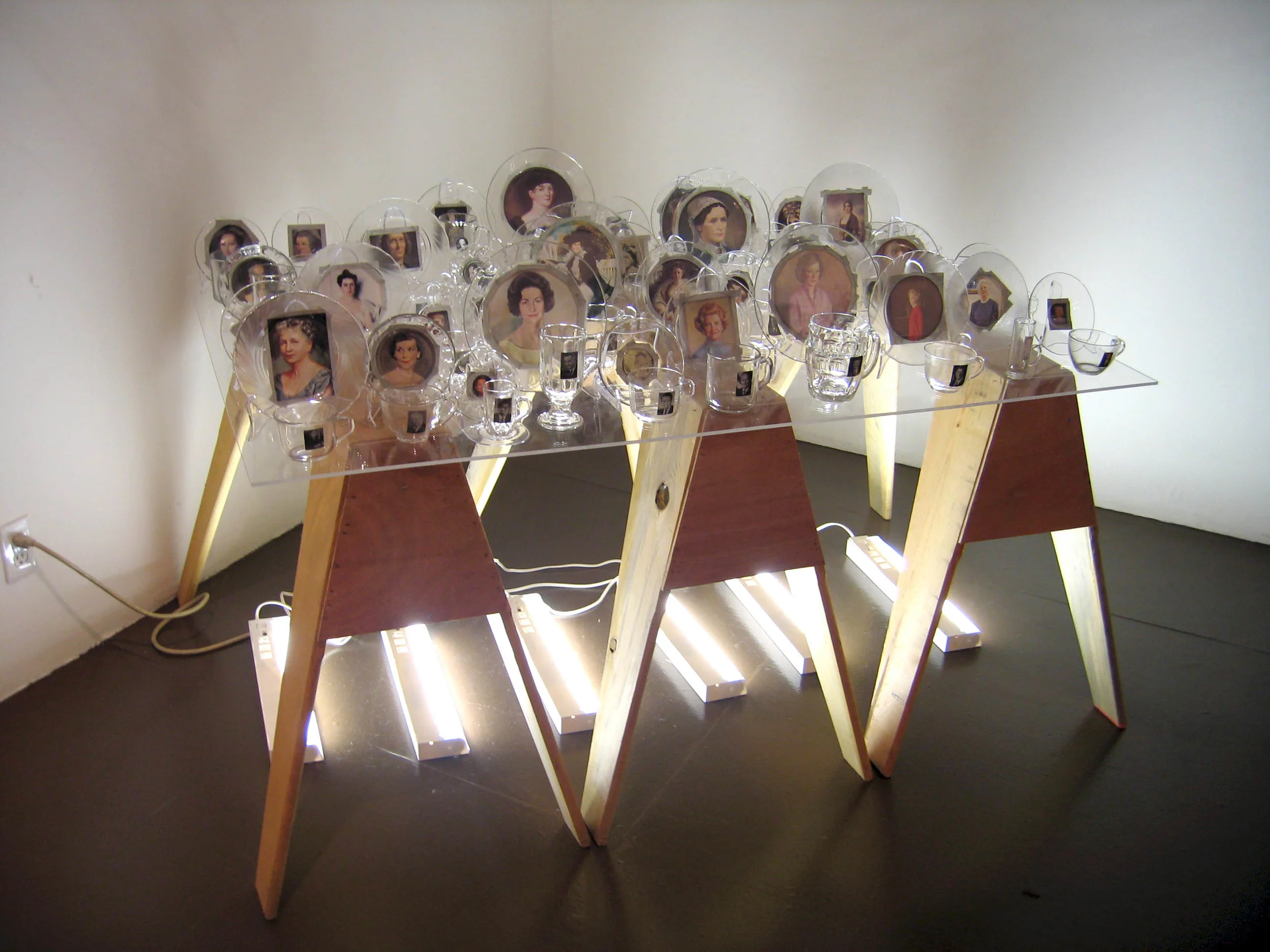 First Love (Installation at Shared Women LACE), 2007, Glass, paper, tape, plexiglass, wood and fluorescent lights 41 cups with president, 41 saucers with first lady, 4 x 3 x 3'