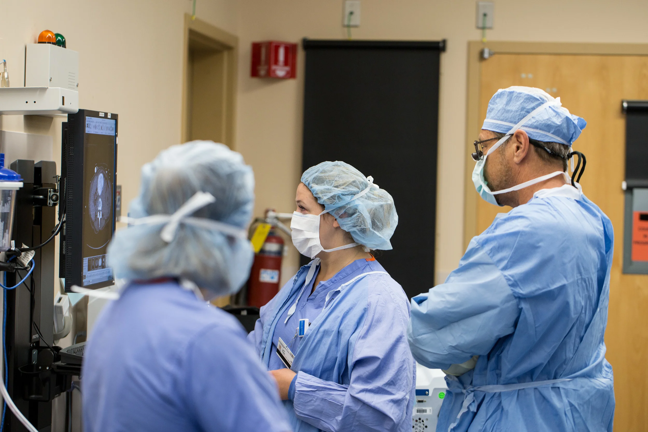  In the operating room, a surgeon and two nurses examine a CT scan sent from the emergency room. 