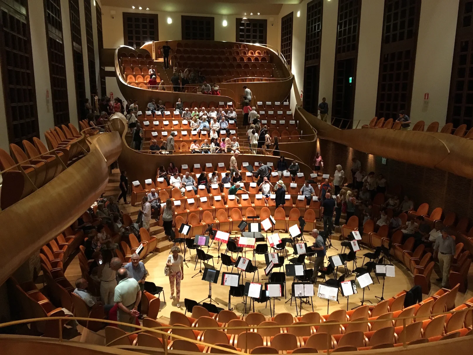 Setting up for rehearsal in the Arvedi Auditorium in the Violin Museum of Cremona. The hall is designed to feel like being inside a string instrument! Here we have a big problem to solve. The fire marshall instituted new regulations a day before and we were told only two thirds of the orchestra could play on the stage...So we put a third of the players in audience seating!