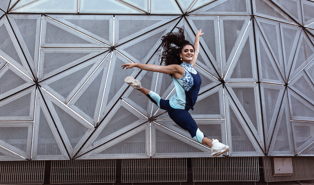 Luca wears the Willow Crop Top in Momentum, Bailey Legging and Blair Singlet in Indigo from the Momentum Collection.