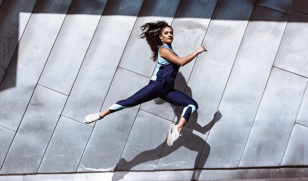 Luca wears the Willow Crop Top in Momentum, Bailey Legging and Blair Singlet in Indigo from the Momentum Collection.