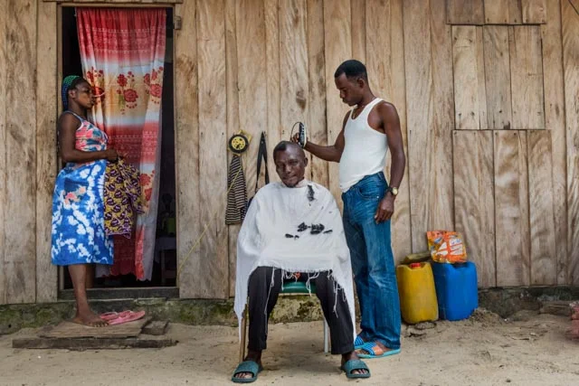A barber cuts one of the fishermen’s hair.