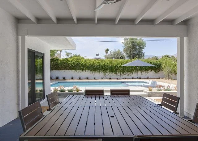 the covered lanai with its denim blue painted floors and silent ceiling fan is my favorite outdoor office. i created a cactus feature wall and a fun collection of rattan mirrors as a backdrop for evening dinner parties that can seat up to ten people.