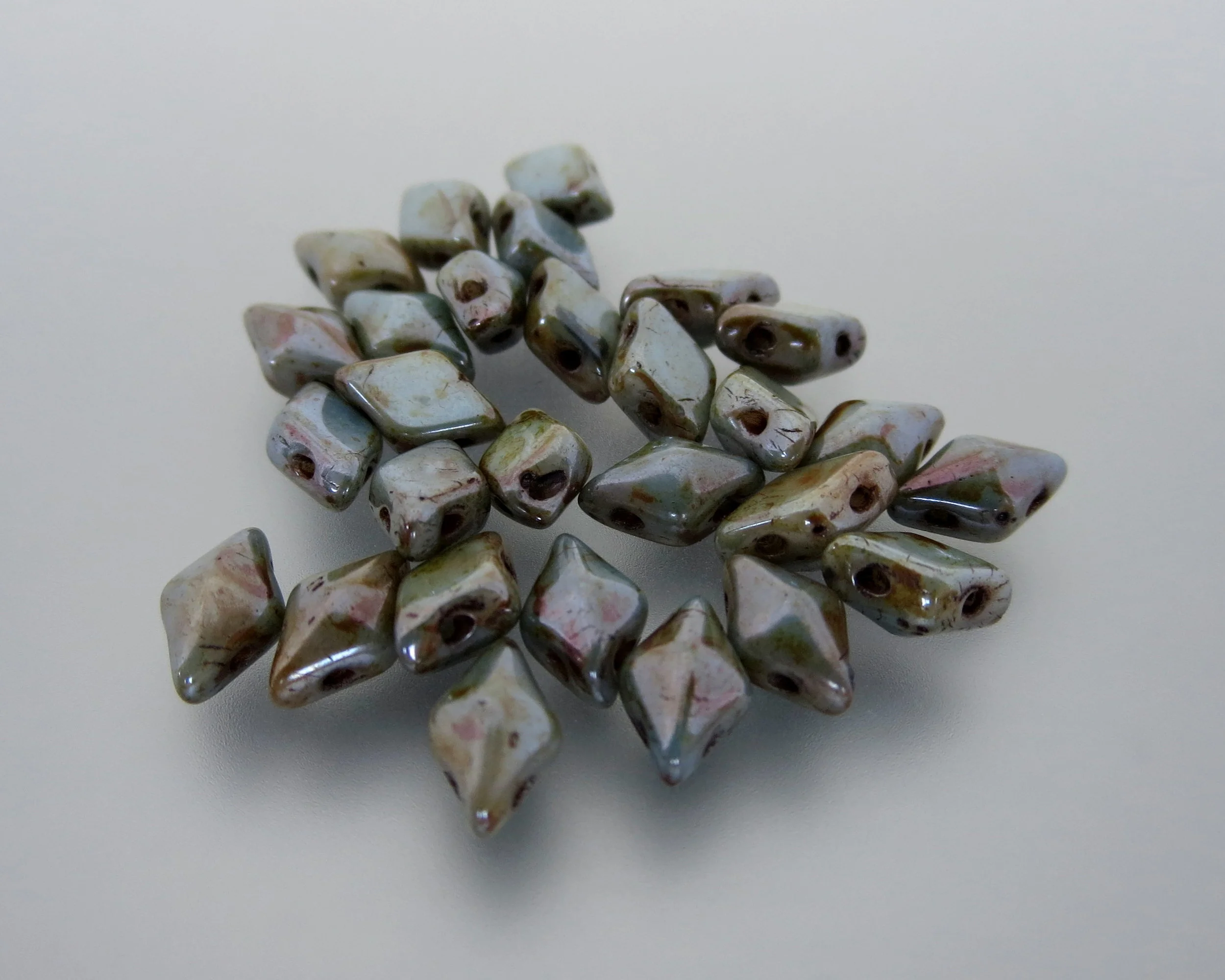 The Buffalo Bead Gallery sells DiamonDuos are a 2-hole Czech pressed glass bead made in the Czech Republic. The diamond shape bead measures 5x8mm (5mm in width and 8mm in length), with a 1mm hole.