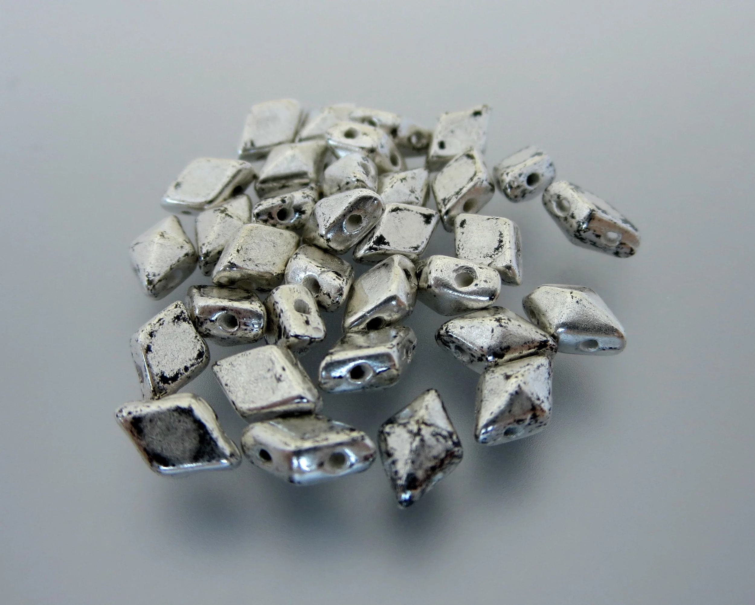 The Buffalo Bead Gallery sells DiamonDuos are a 2-hole Czech pressed glass bead made in the Czech Republic. The diamond shape bead measures 5x8mm (5mm in width and 8mm in length), with a 1mm hole.