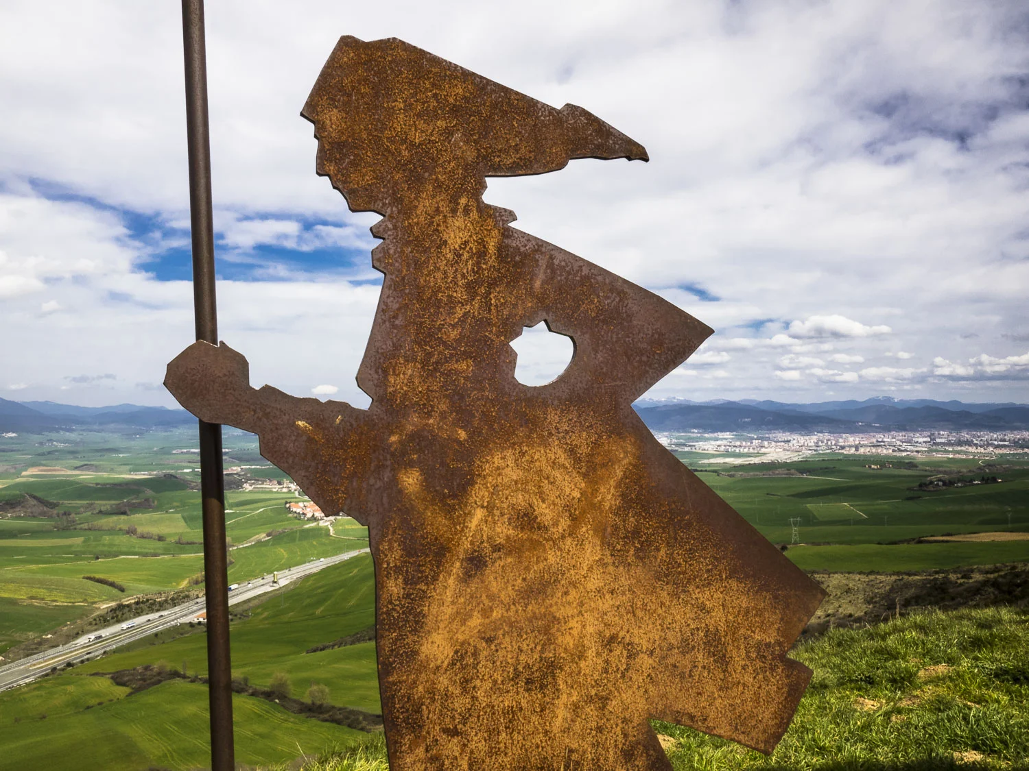 This sculpture of pilgrim silhouettes is on ALTO DEL PERDON , a hilltop west of Pamplona, which appears here in the distance.
