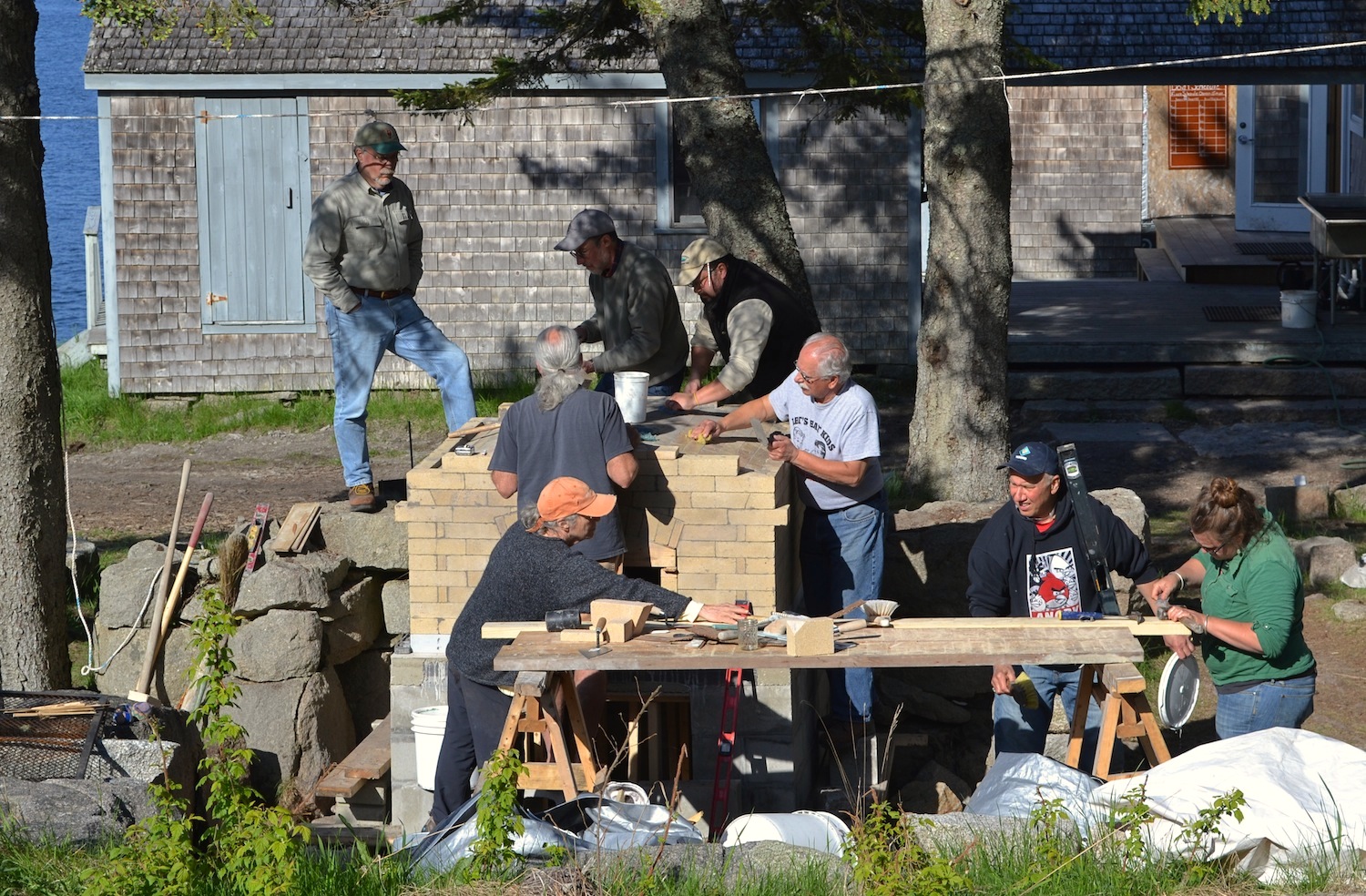 Pat Manley helps masonry workshop participants lay the last of the fire brick over the arched roof of the oven.