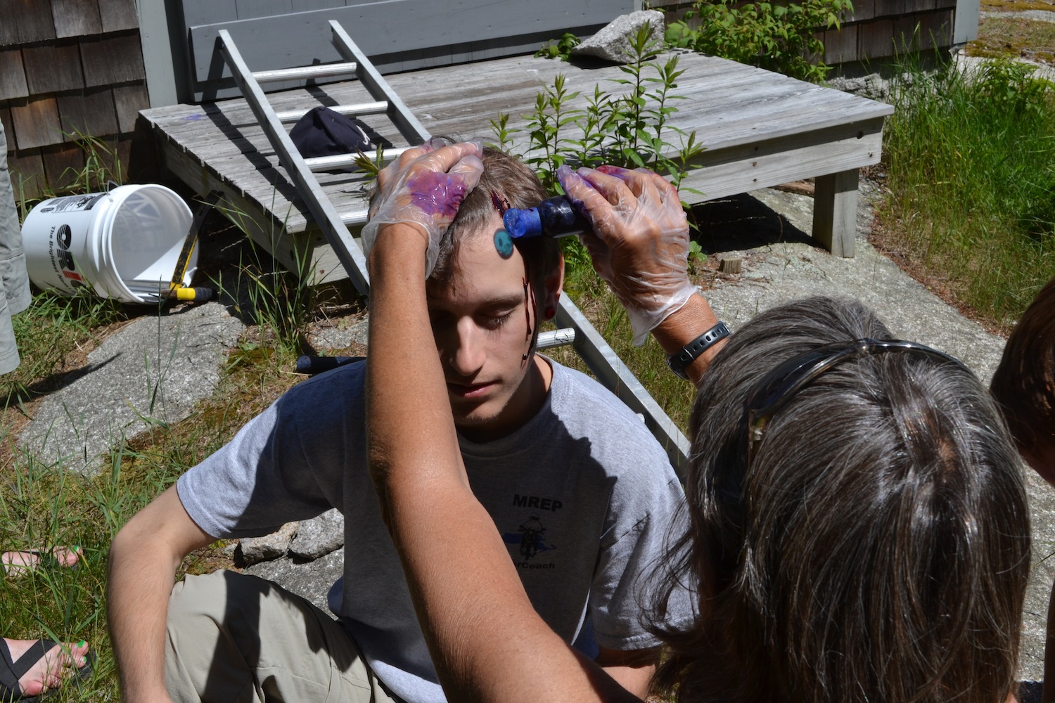 A student gets moulage to act the part of a patient who fell off a ladder in a scenario