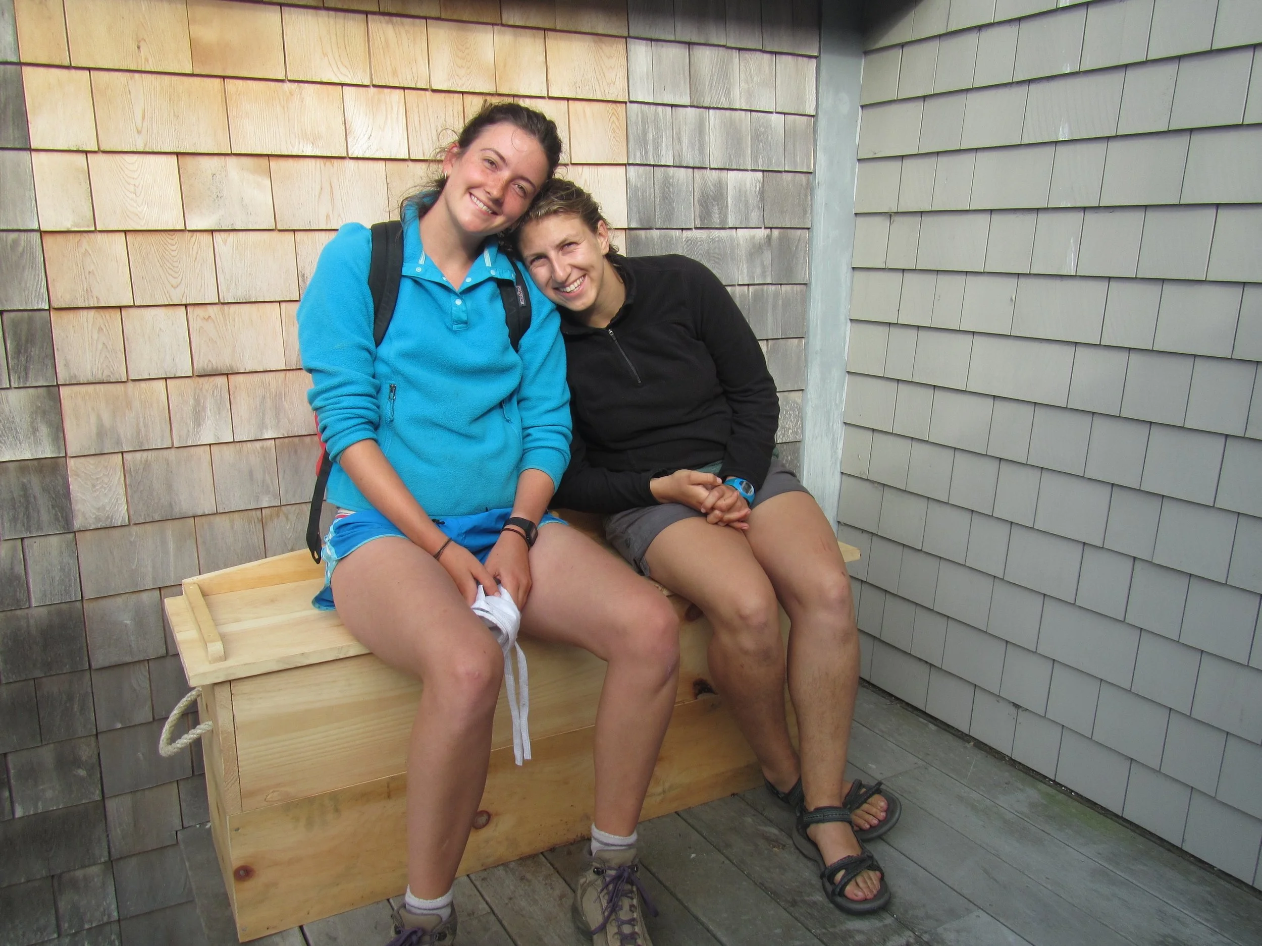 Science Educator, Isabelle, and Teaching Assistant, Lilla, sitting on the finished worm composting bench on the back deck by the galley.