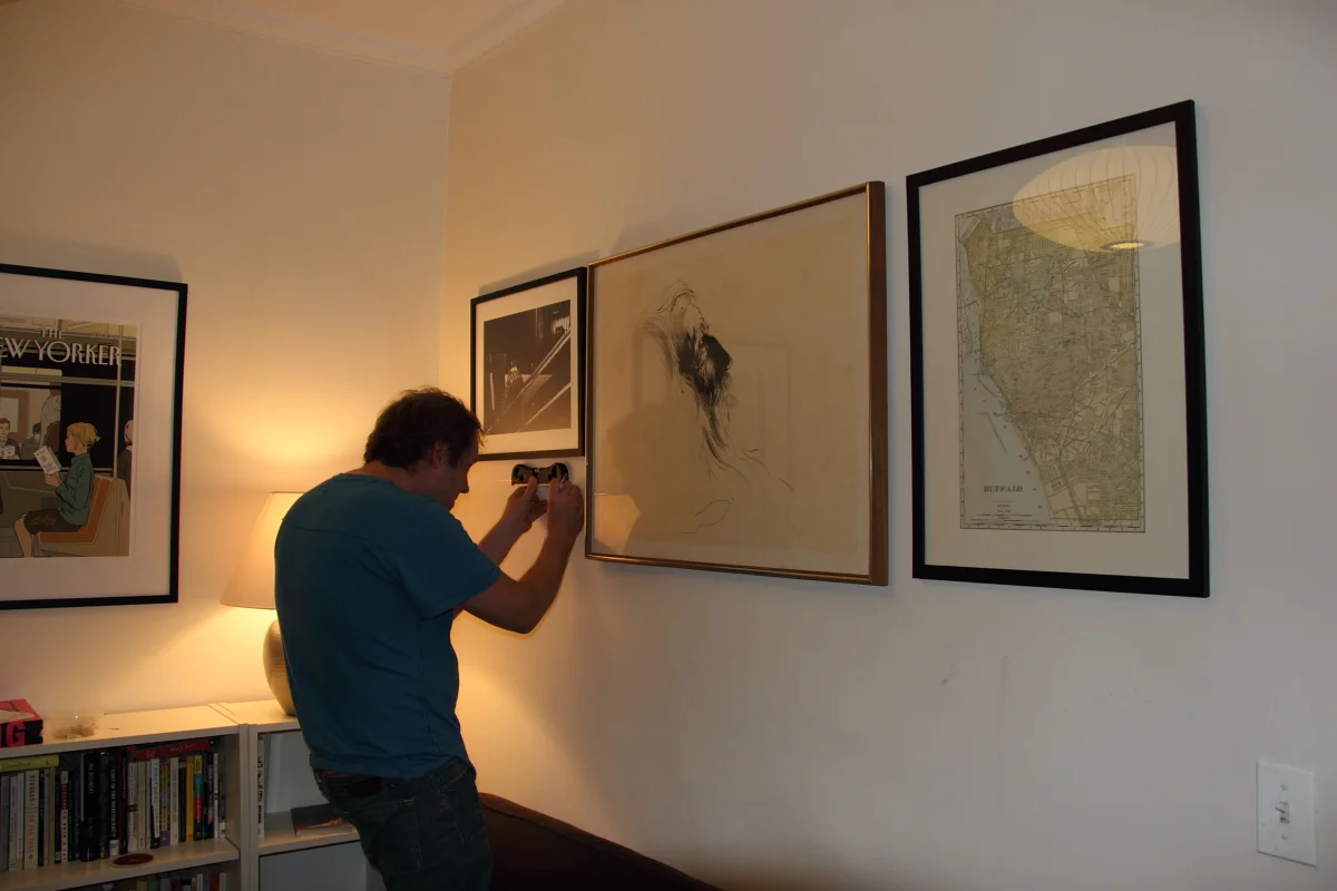     Douglas Kay 
 is living up to his reputation as a talented and meticulous hanger of framed 
art. Here you see him carefully measuring levels so that the frames will
 be perfectly aligned in his composition.      
