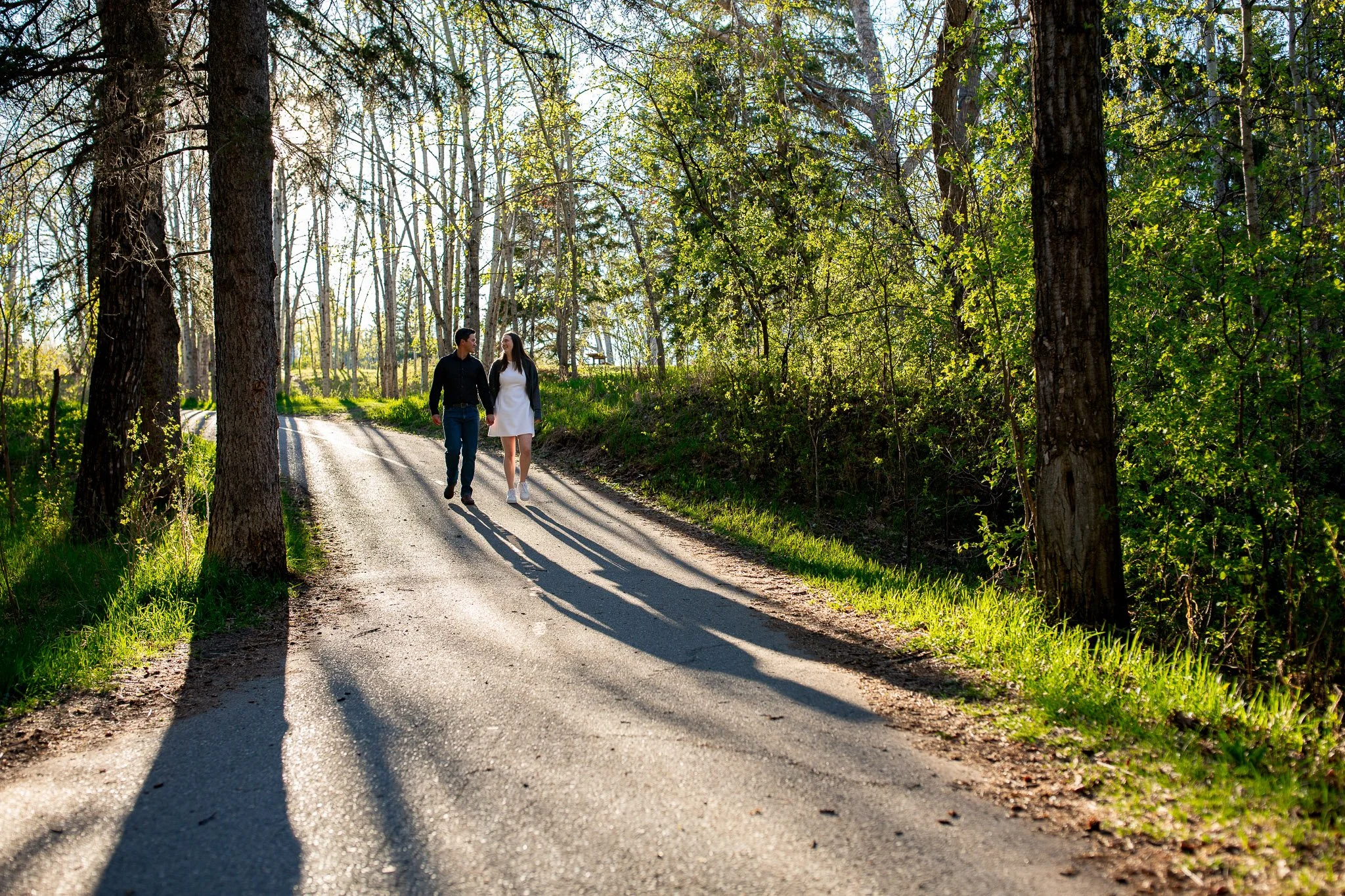 A couple walking together through the forest trails of Shannon Terrace in Fish Creek Park during a relaxed Calgary engagement session.