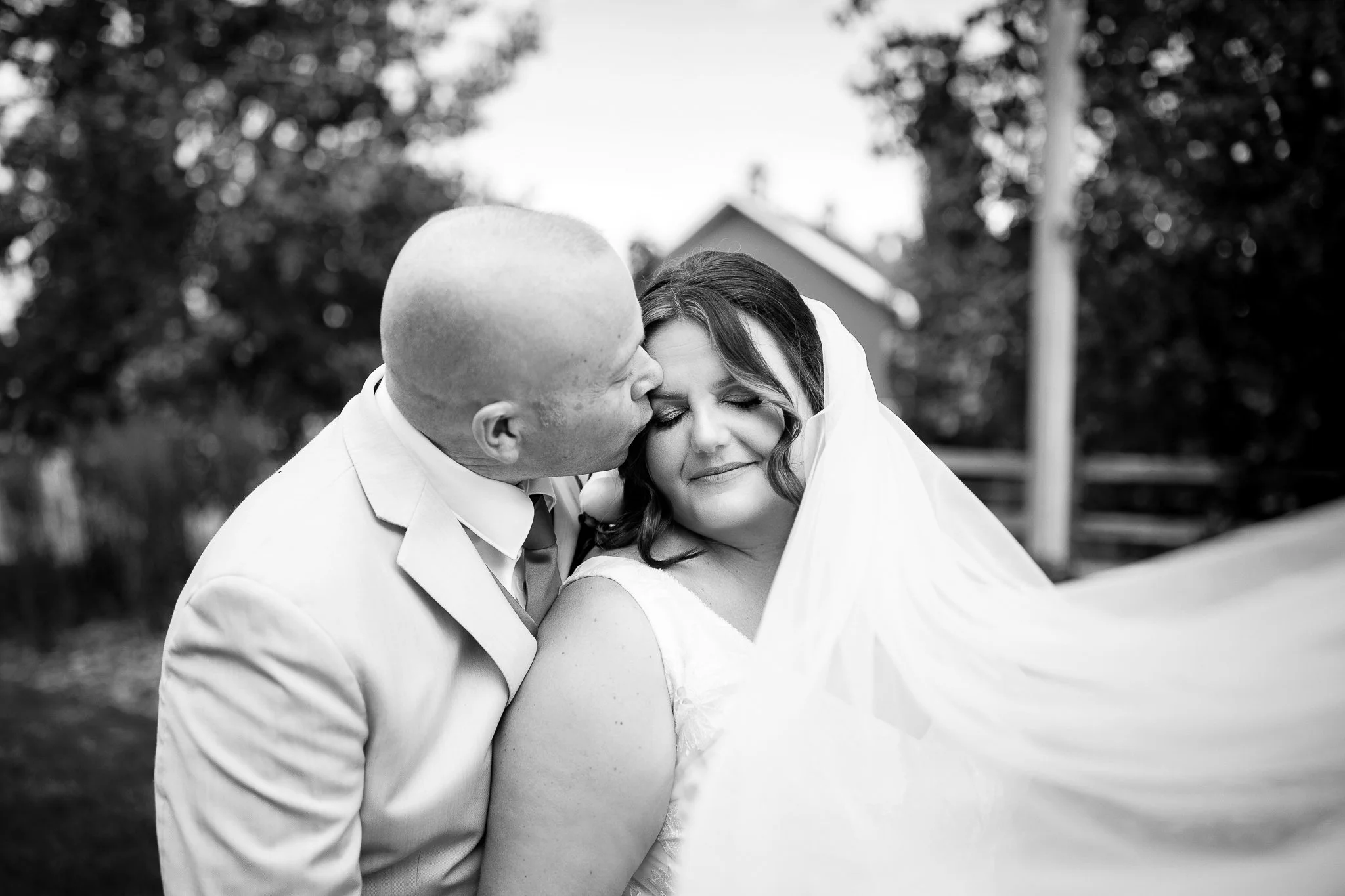Bride and groom embracing in front of the barn at Prairie Lane Barn in Calgary, Alberta
