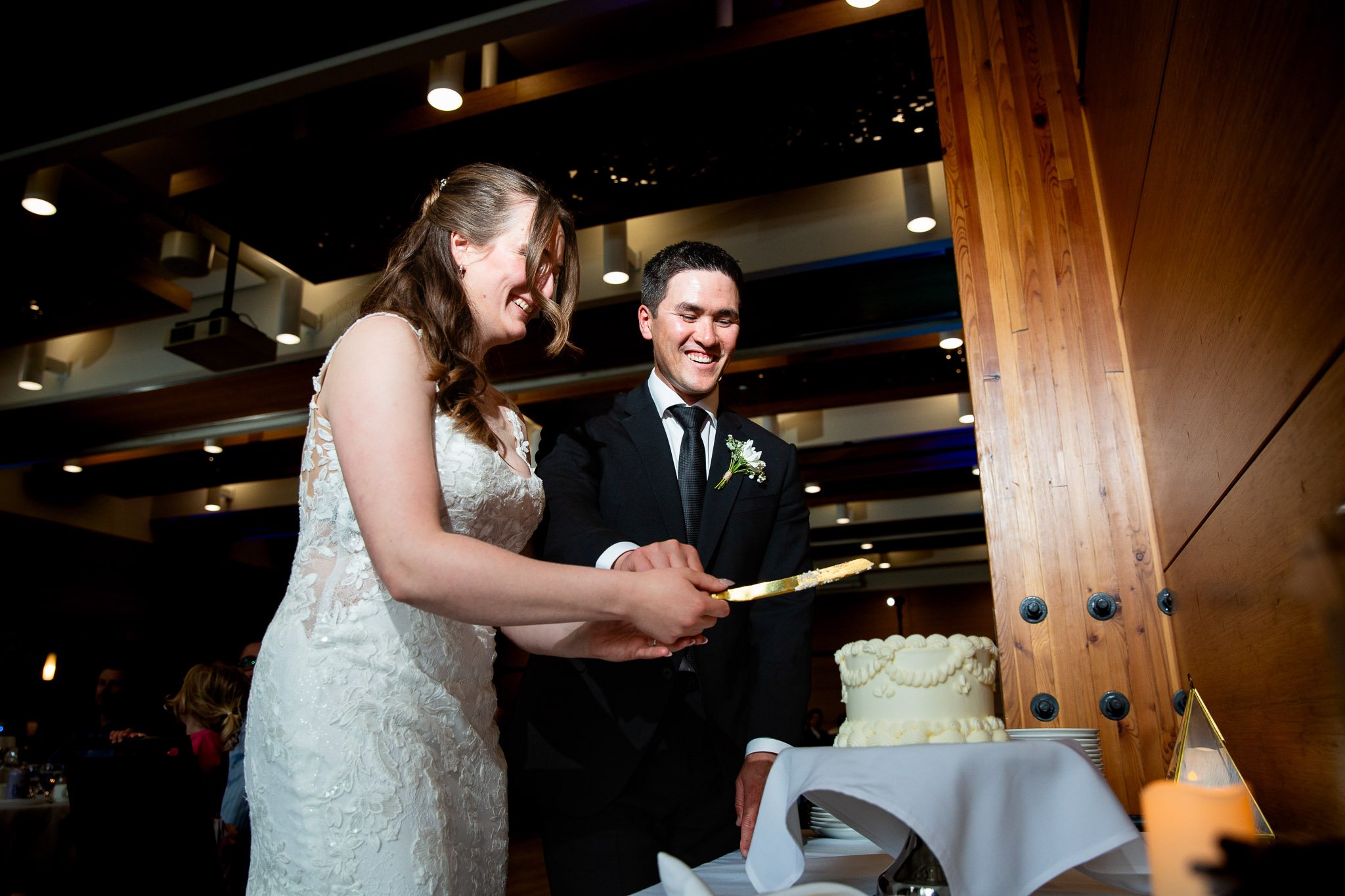 Robert and Megan cutting the cake surrounded by family and friends.