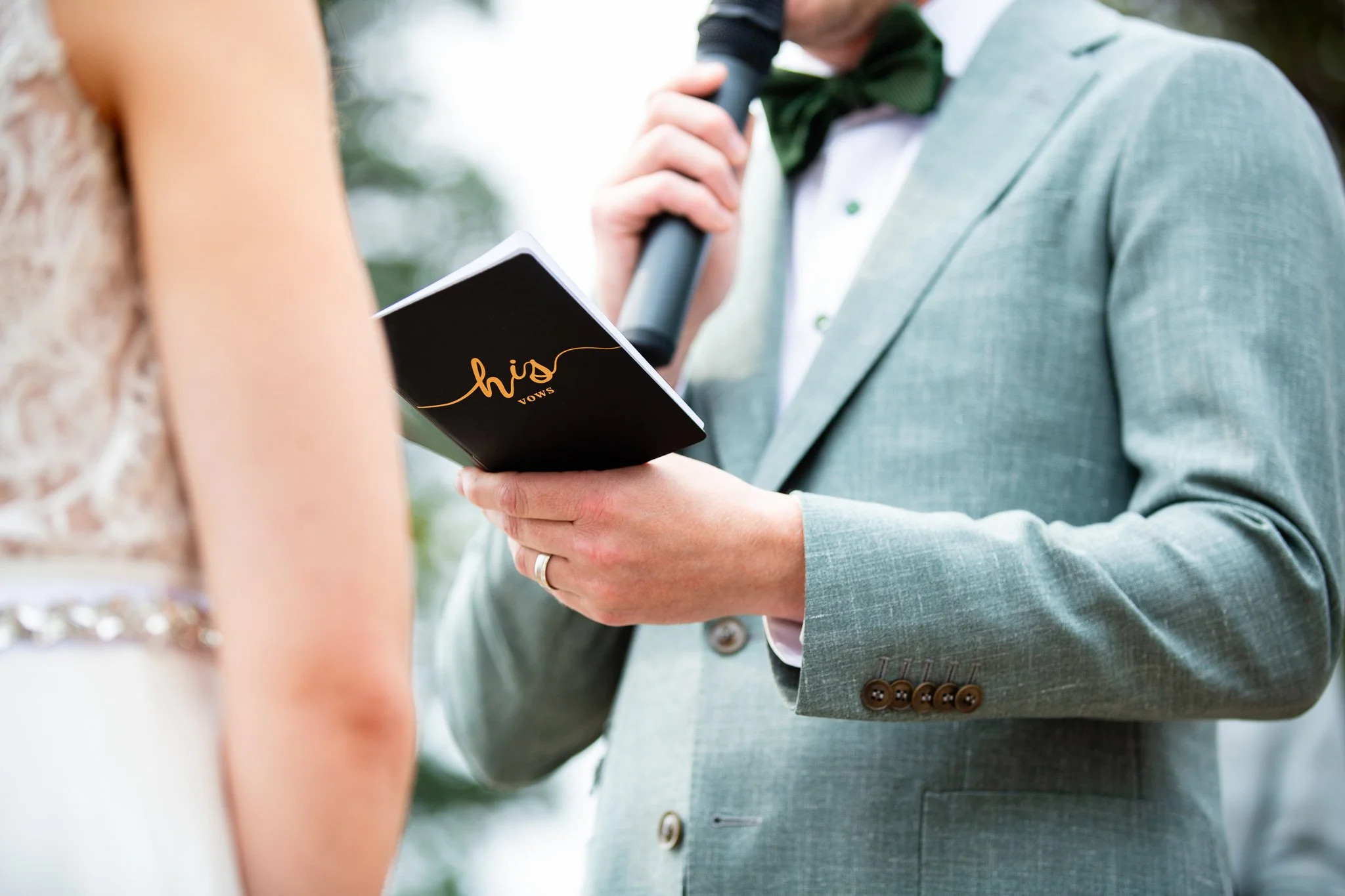 Bride and groom exchanging vows at an outdoor woodland ceremony with mountains in the background near Calgary