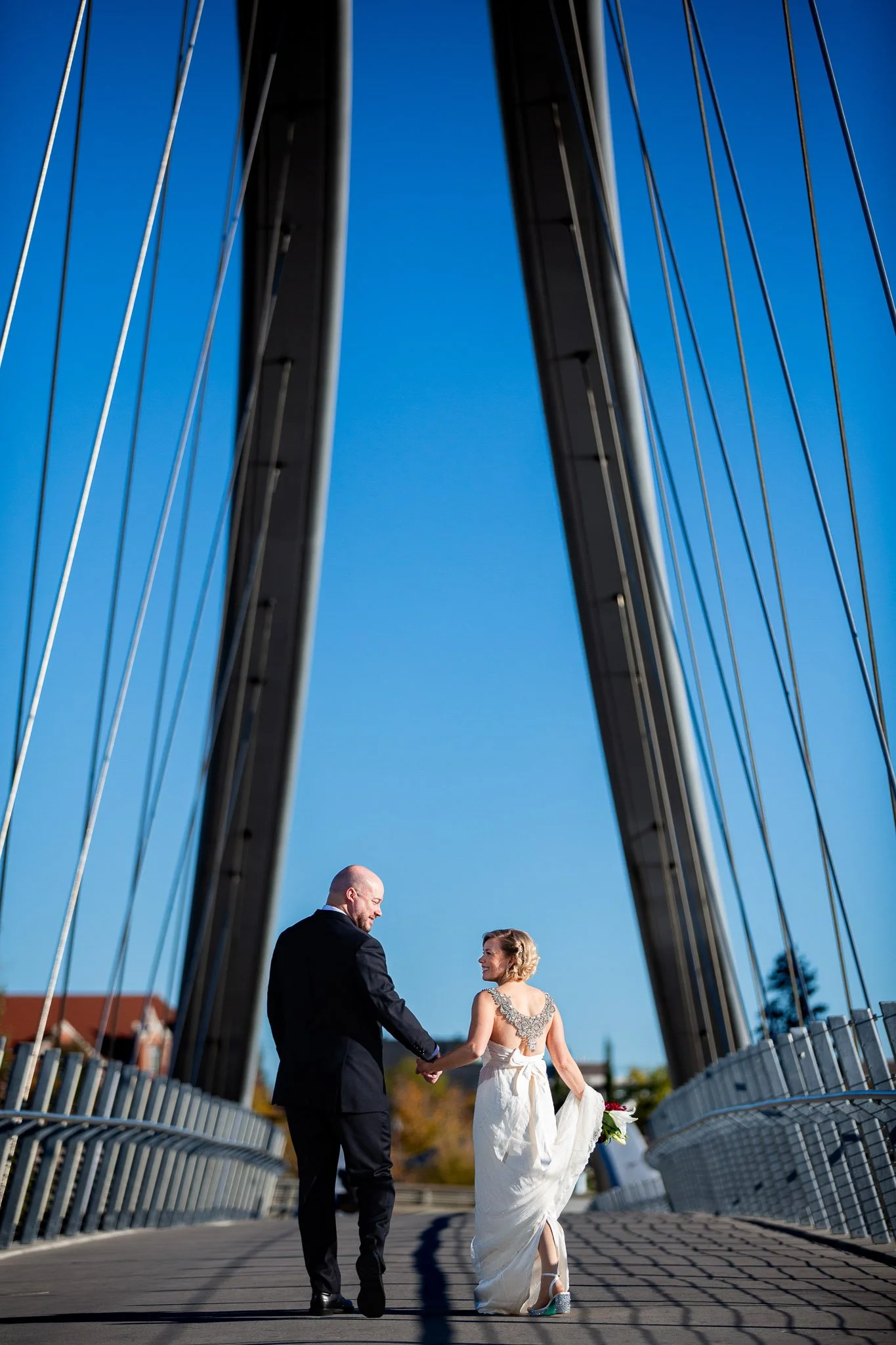 Wedding couple walking along the RiverWalk near the Simmons Building in Calgary.