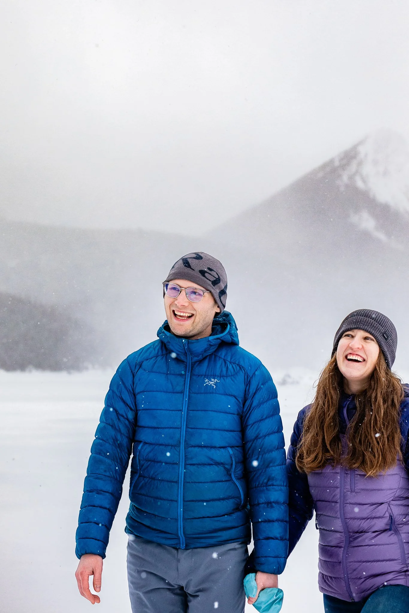 Tyler and Taryn walk hand in hand through a snowy trail during their winter Calgary engagement session in Kananaskis.
