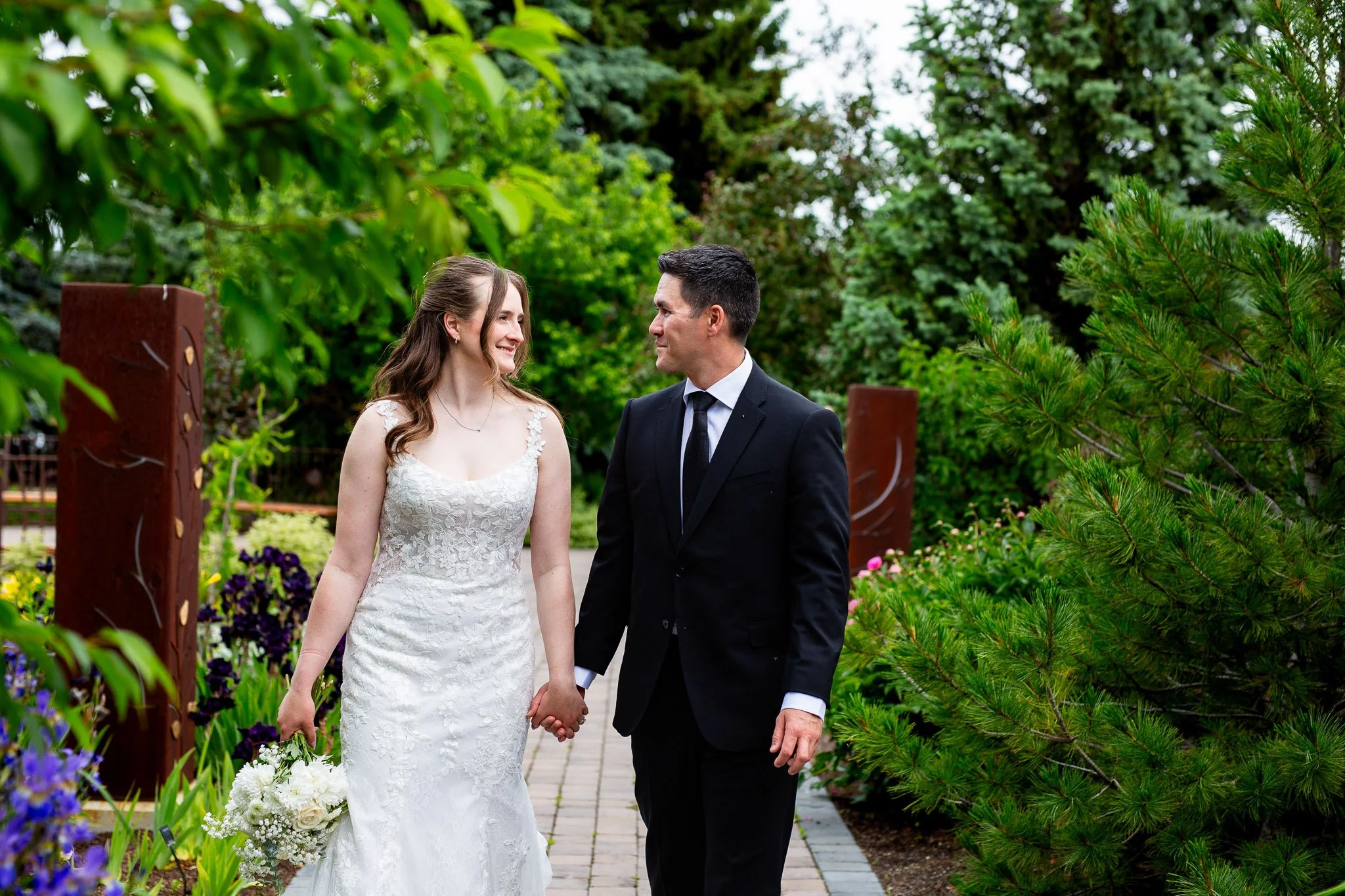 Romantic wedding portraits surrounded by lush greenery and blooming flowers at the Calgary Zoo.