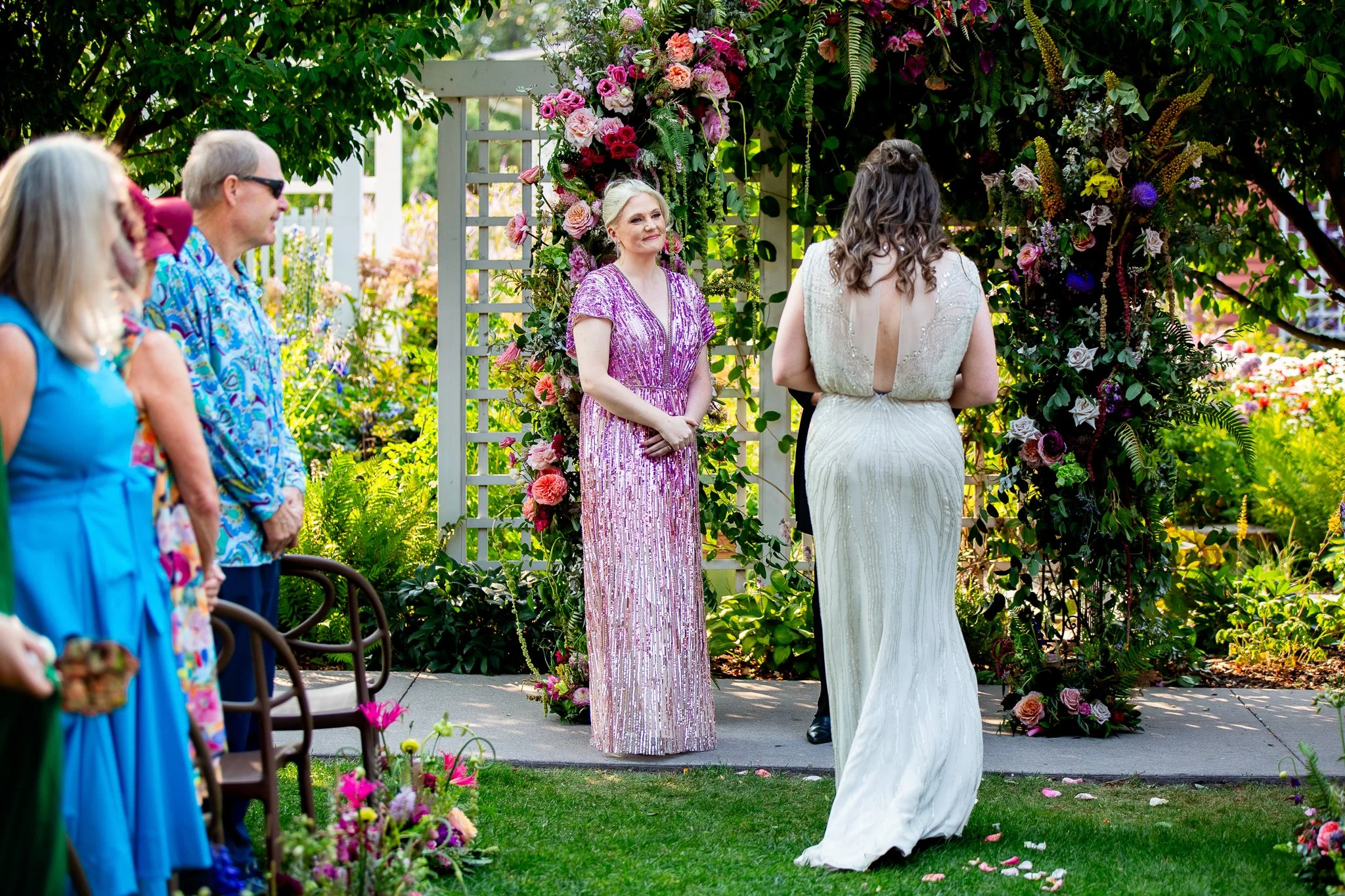 A beatuful garden wedding ceremony beneath a large floral arch at The Deane House Calgary