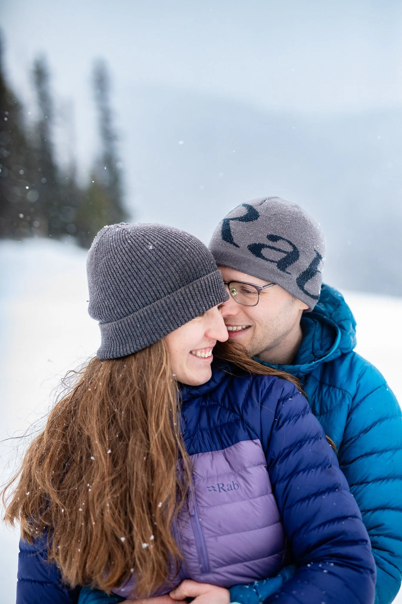 Couple embracing in a misty winter landscape during their Kananaskis engagement photos on a frosty evening.